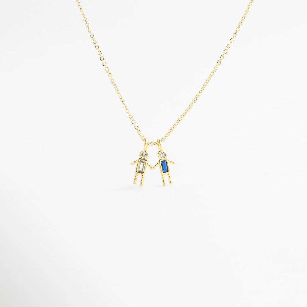 Dije dorado de niño con zirconia celeste en diseño delicado, Detalle de colgante con piedra celeste y figura masculina minimalista, Collar con dije pequeño de niño y zirconia celeste brillante, Colgante en oro 18K con zirconia celeste y acabado pulido, Detalle de collar con figura de niño y piedra celeste