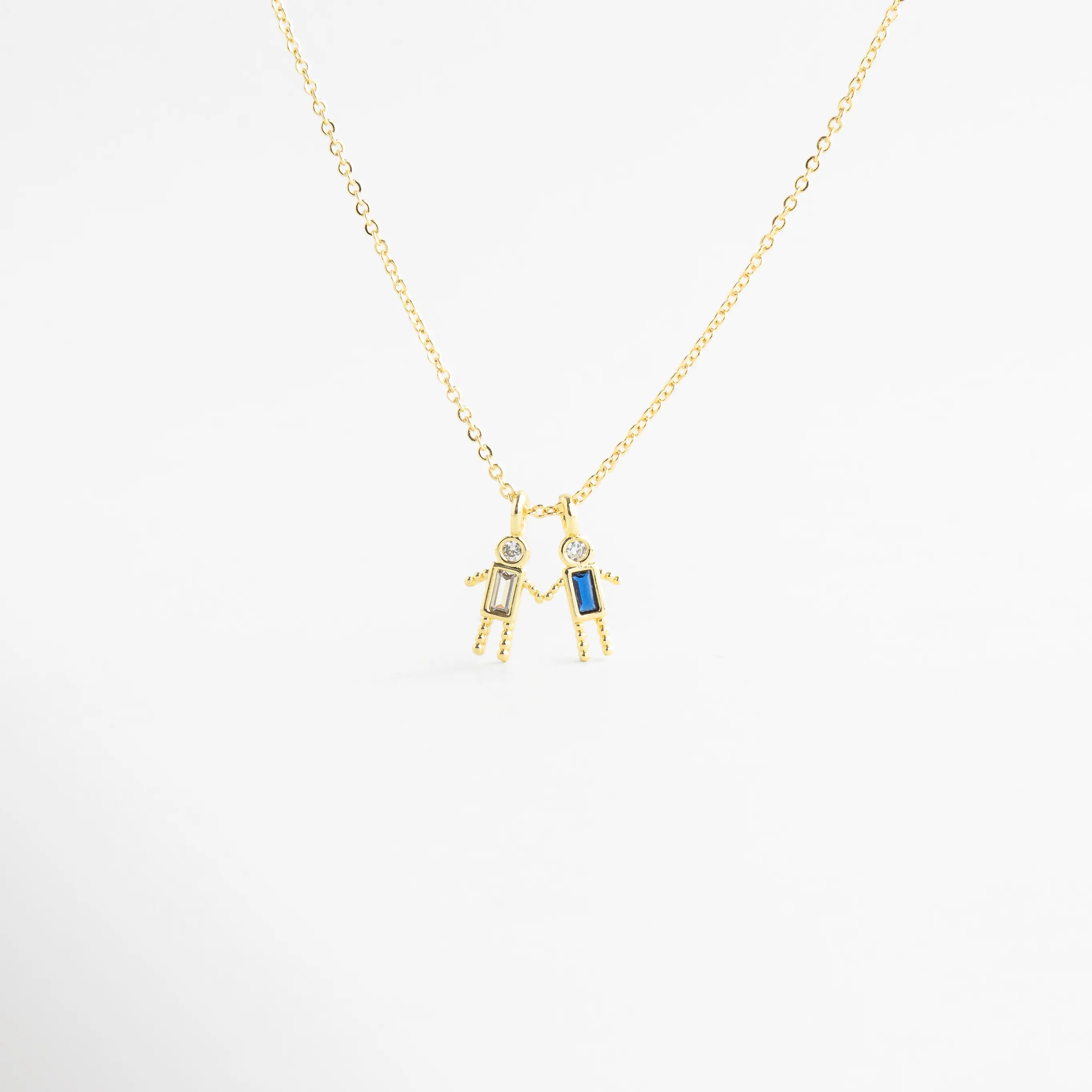 Dije dorado de niño con zirconia celeste en diseño delicado, Detalle de colgante con piedra celeste y figura masculina minimalista, Collar con dije pequeño de niño y zirconia celeste brillante, Colgante en oro 18K con zirconia celeste y acabado pulido, Detalle de collar con figura de niño y piedra celeste