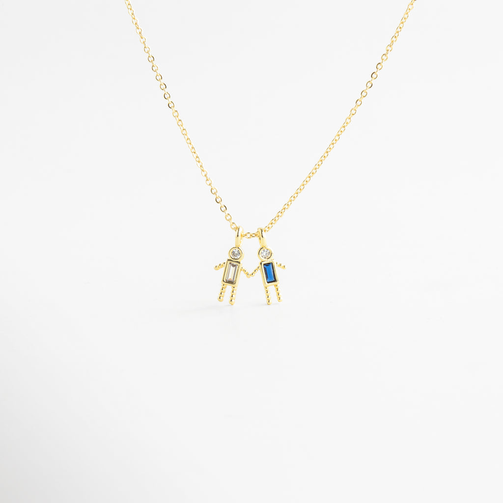 Dije dorado de niño con zirconia rosa en diseño delicado, Detalle de colgante con piedra rosa y figura masculina minimalista, Collar con dije pequeño de niño y zirconia rosa brillante, Colgante en oro 18K con zirconia rosa y acabado pulido, Detalle de collar con figura de niño y piedra rosa