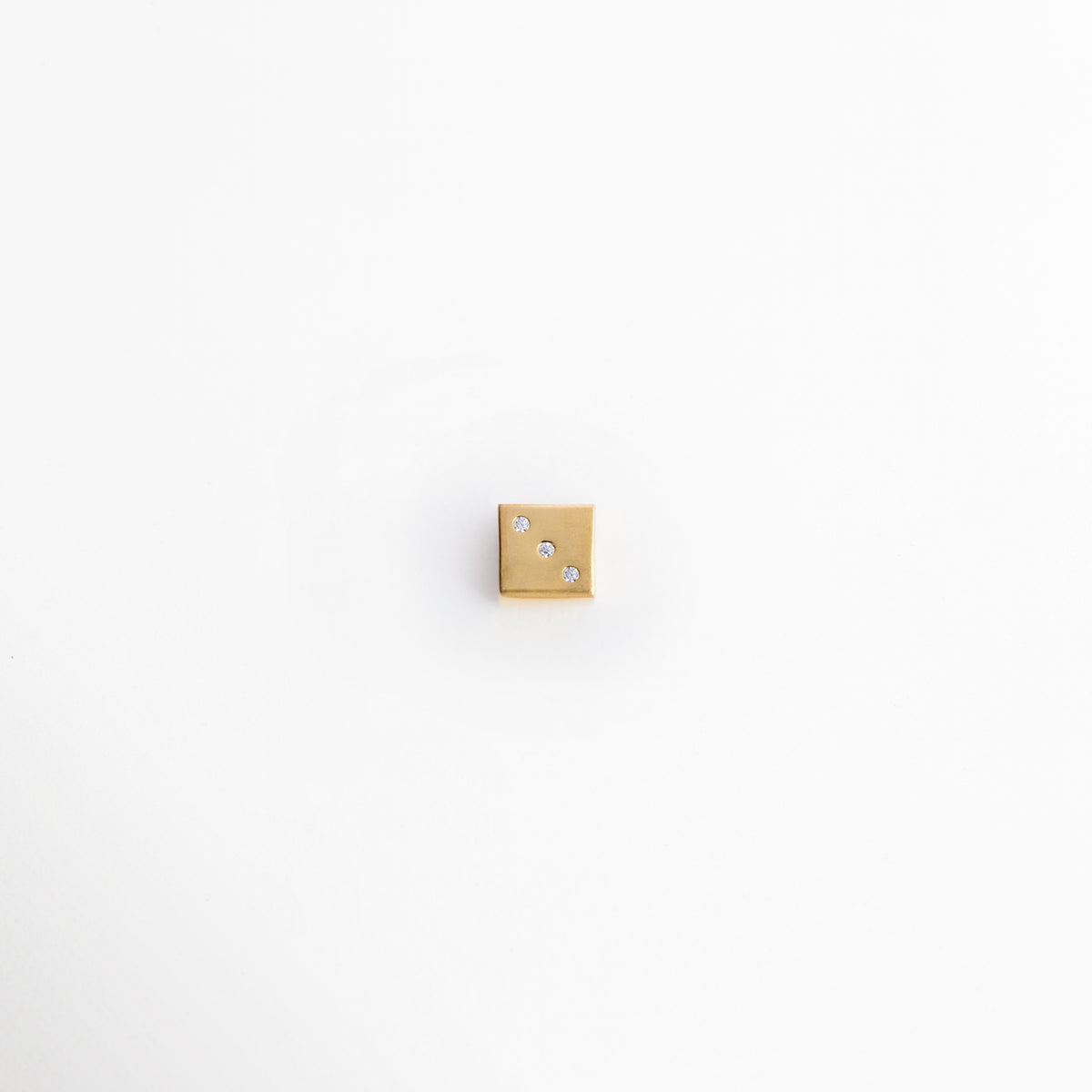 Charm Dado de cobre enchapado en oro 14K con forma cúbica de 0.8 cm y puntos de zirconia incrustada, vista frontal sobre fondo blanco, Vista de frente de dije tridimensional en forma de dado dorado con pequeños cristales de zirconia como puntos numéricos, Plano general de charm geométrico cúbico en tono oro brillante de 0.8 cm de ancho sobre fondo neutro, Charm Dado destacando las incrustaciones de pedrería transparente en sus caras metálicas pulidas. 