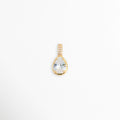 Charm Glow con gran circonia transparente en forma de gota o lágrima y reasa vertical con micro-pavé, vista frontal sobre fondo blanco, Dije en forma de lágrima de 1.1 x 0.7 cm con gema de circonia brillante y engaste de bisel sobre metal dorado galvanizado, Vista de frente de dije charm de cobre dorado con gema de talla pera y asa decorada con pedrería incrustada, Charm de circonia transparente de corte gota con recubrimiento galvanizado brillante.