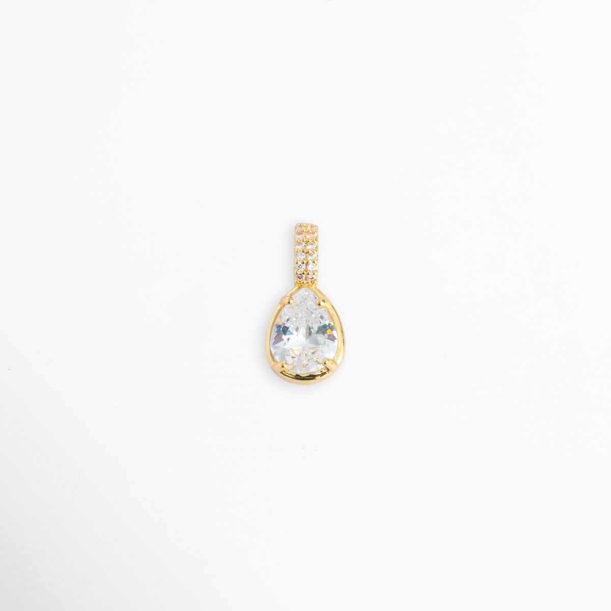 Charm Glow con gran circonia transparente en forma de gota o lágrima y reasa vertical con micro-pavé, vista frontal sobre fondo blanco, Dije en forma de lágrima de 1.1 x 0.7 cm con gema de circonia brillante y engaste de bisel sobre metal dorado galvanizado, Vista de frente de dije charm de cobre dorado con gema de talla pera y asa decorada con pedrería incrustada, Charm de circonia transparente de corte gota con recubrimiento galvanizado brillante.