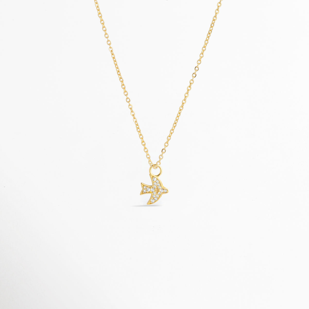 Charm Avión Zirconias montado como dije central en una fina cadena dorada sobre fondo blanco, Vista de collar con dije pequeño de avión enchapado en oro con circonias brillantes de 1.4 cm, Perspectiva de gargantilla delicada con dije colgante en forma de avión dorado con pedrería, Muestra de escala del charm de avión incrustado con circonias en una cadena delgada enchapada en oro.