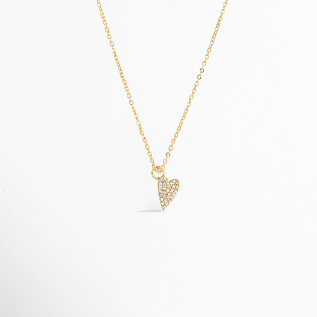 Charm Corazón Zirconias montado como dije central en una fina cadena dorada sobre fondo blanco, Vista de collar con dije pequeño de corazón estilizado enchapado en oro con circonias brillantes de 1.2 cm, Perspectiva de gargantilla delicada con dije colgante en forma de corazón dorado con pedrería, Muestra de escala del charm de corazón incrustado con circonias en una cadena delgada enchapada en oro.
