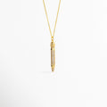 Charm Lápiz de cobre enchapado en oro de 4.2 cm de largo con cuerpo cuajado en pavé de circonias transparentes, vista frontal sobre fondo blanco, Vista de frente de dije estilizado en forma de lápiz dorado con incrustaciones de pedrería brillante suspendido de una fina cadena, Plano general de charm tridimensional en forma de lápiz enchapado en oro con detalles de circonias cristalinas sobre fondo neutro, Charm Lápiz destacando la punta dorada pulida y el resplandor