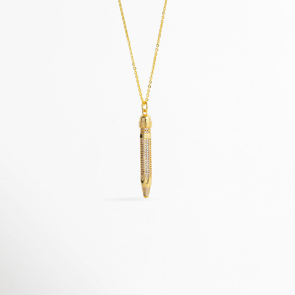 Charm Lápiz de cobre enchapado en oro de 4.2 cm de largo con cuerpo cuajado en pavé de circonias transparentes, vista frontal sobre fondo blanco, Vista de frente de dije estilizado en forma de lápiz dorado con incrustaciones de pedrería brillante suspendido de una fina cadena, Plano general de charm tridimensional en forma de lápiz enchapado en oro con detalles de circonias cristalinas sobre fondo neutro, Charm Lápiz destacando la punta dorada pulida y el resplandor