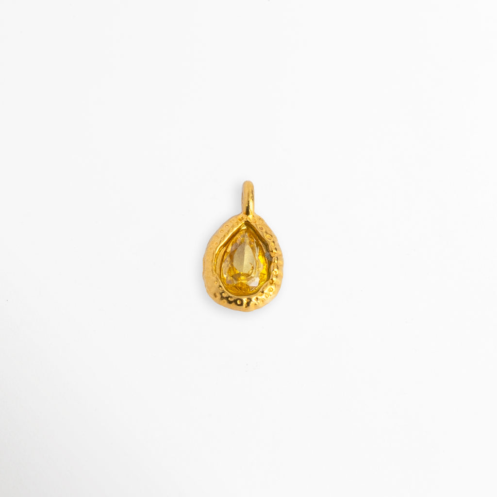 Charm Gota Amarillo con circonia en tono amarillo vibrante de corte lágrima y marco orgánico texturizado en tono dorado, vista frontal sobre fondo blanco. Dije de 1.2 x 0.7 cm en forma de gota con gema amarilla engastada en acero inoxidable con baño de oro, Vista de frente de dije charm de acero dorado con circonia amarilla de corte pera y borde artesanal, Charm de acero inoxidable enchapado en oro con piedra de circonia amarillo canario sobre fondo claro.