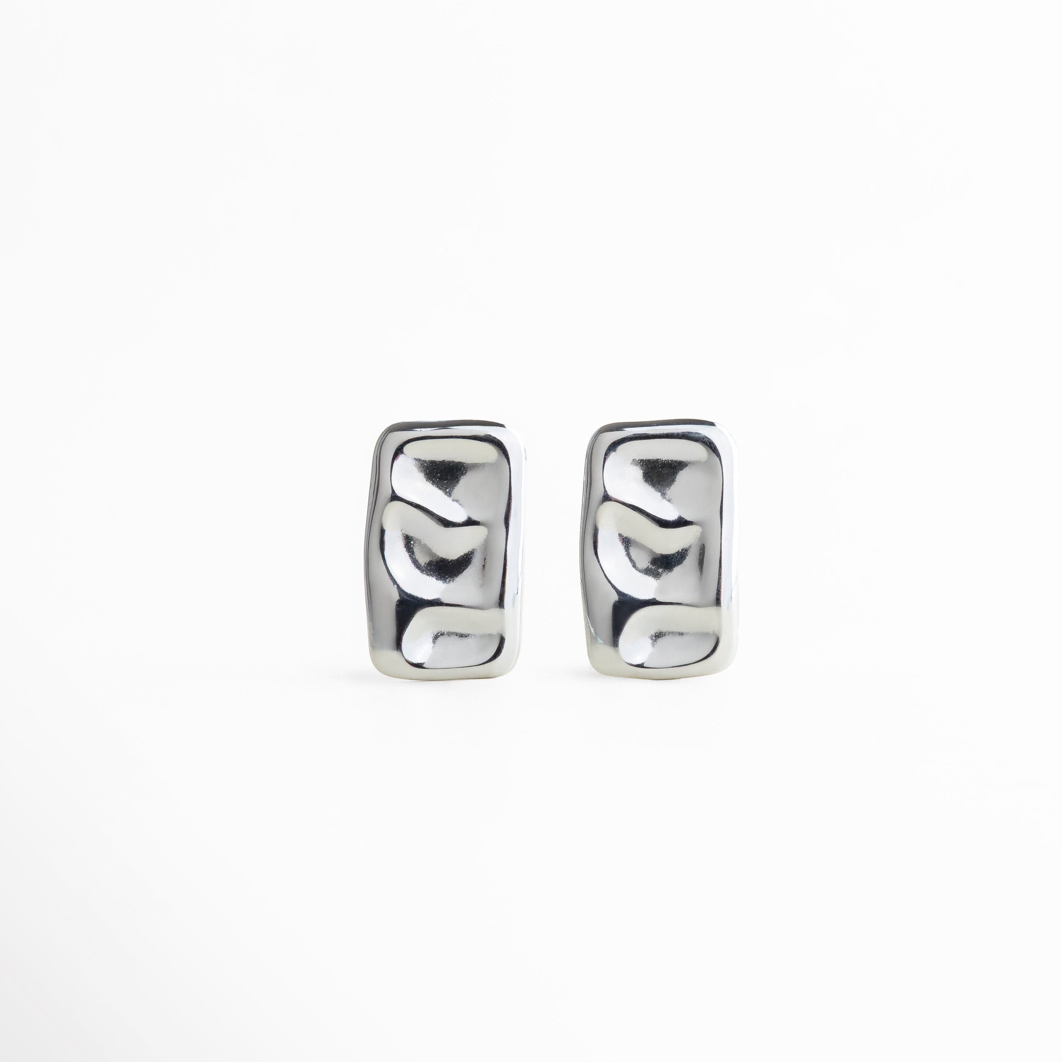 aretes rectangulares plateados, aretes estilo líquido, joyería minimalista mujer, aretes modernos plateados, aretes brillantes efecto ondulado, accesorios elegantes plateados, aretes geométricos chic, aretes statement pequeños