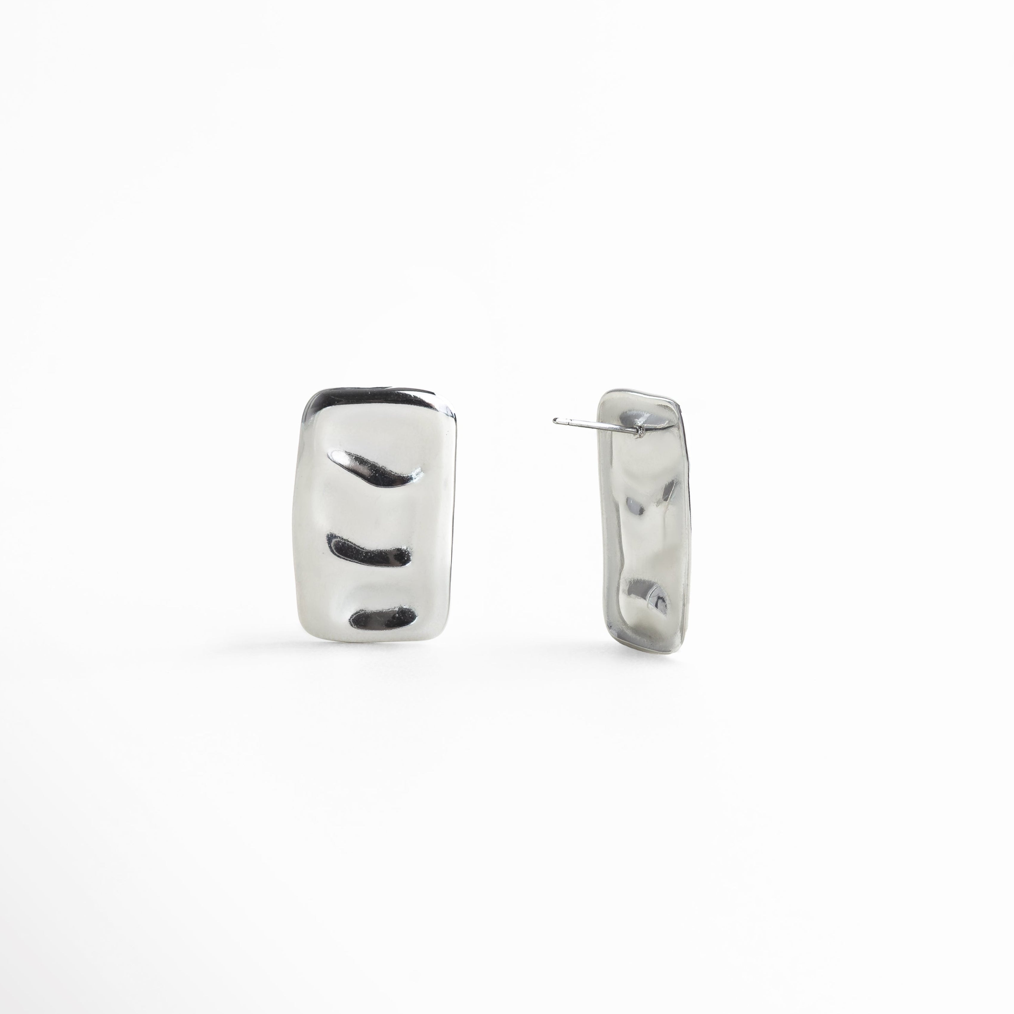 aretes escultóricos plateados, aretes rectangulares ondulados, joyería moderna textura líquida, accesorios plateados sofisticados, aretes geométricos contemporáneos, aretes metálicos brillantes, aretes diseño artístico, joyería minimalista plateada