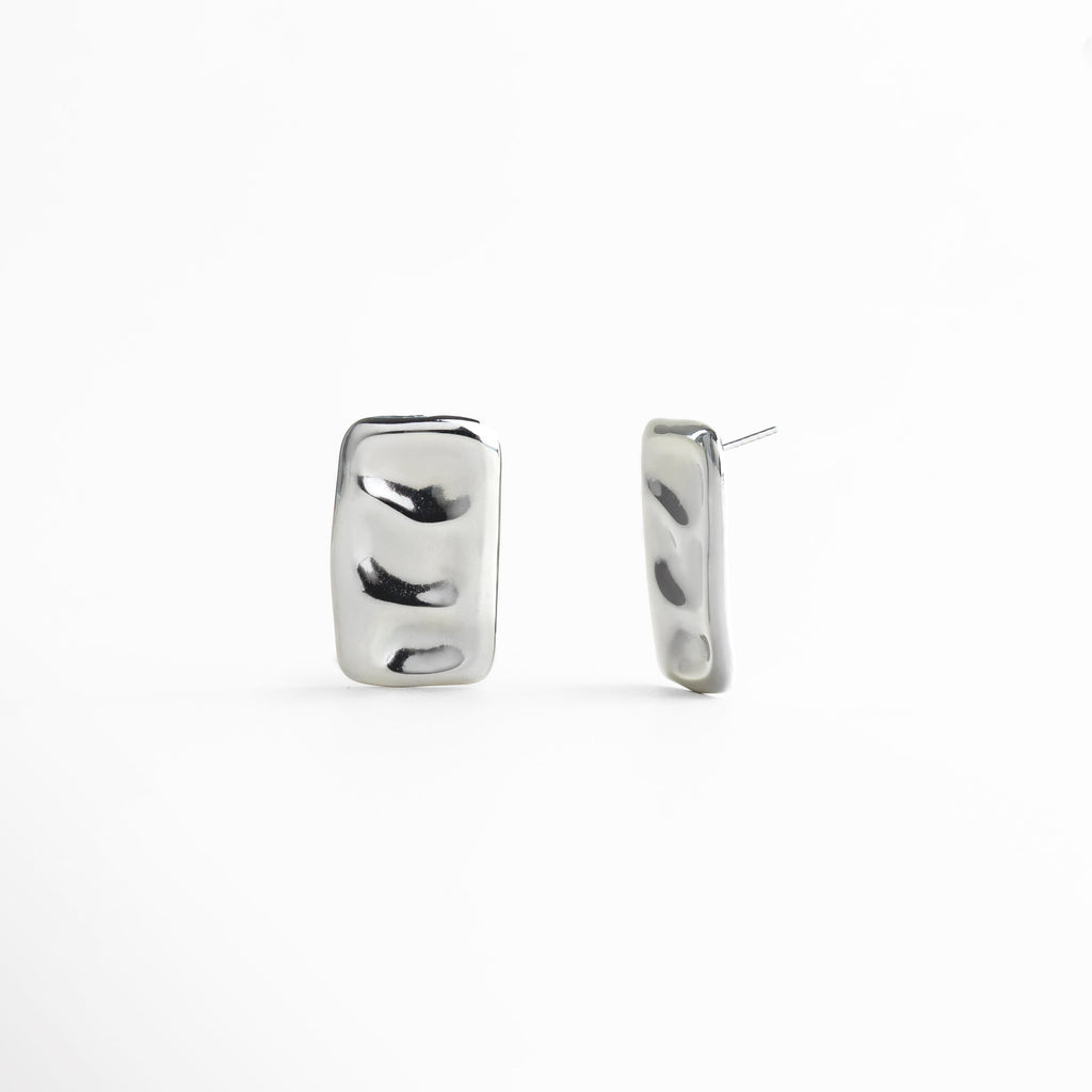 aretes plateados vista lateral, aretes rectangulares elegantes, aretes modernos para mujer, joyería plateada pulida, aretes minimalistas contemporáneos, accesorios plateados de diseño, aretes textura fluida, aretes pequeños elegantes