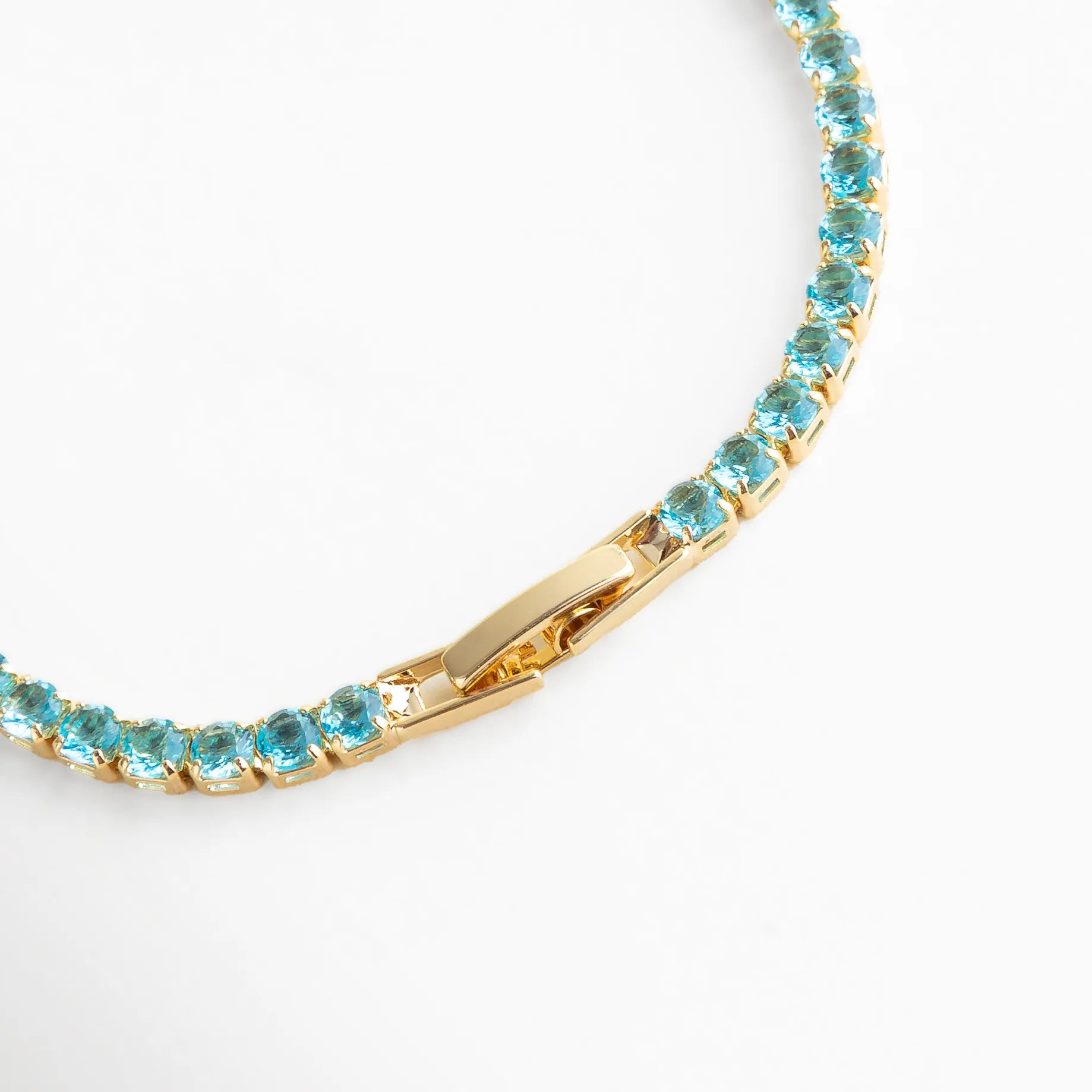 Cierre metálico dorado con acabado pulido y cristales azul cielo, aportando brillo y sofisticación a cualquier look.