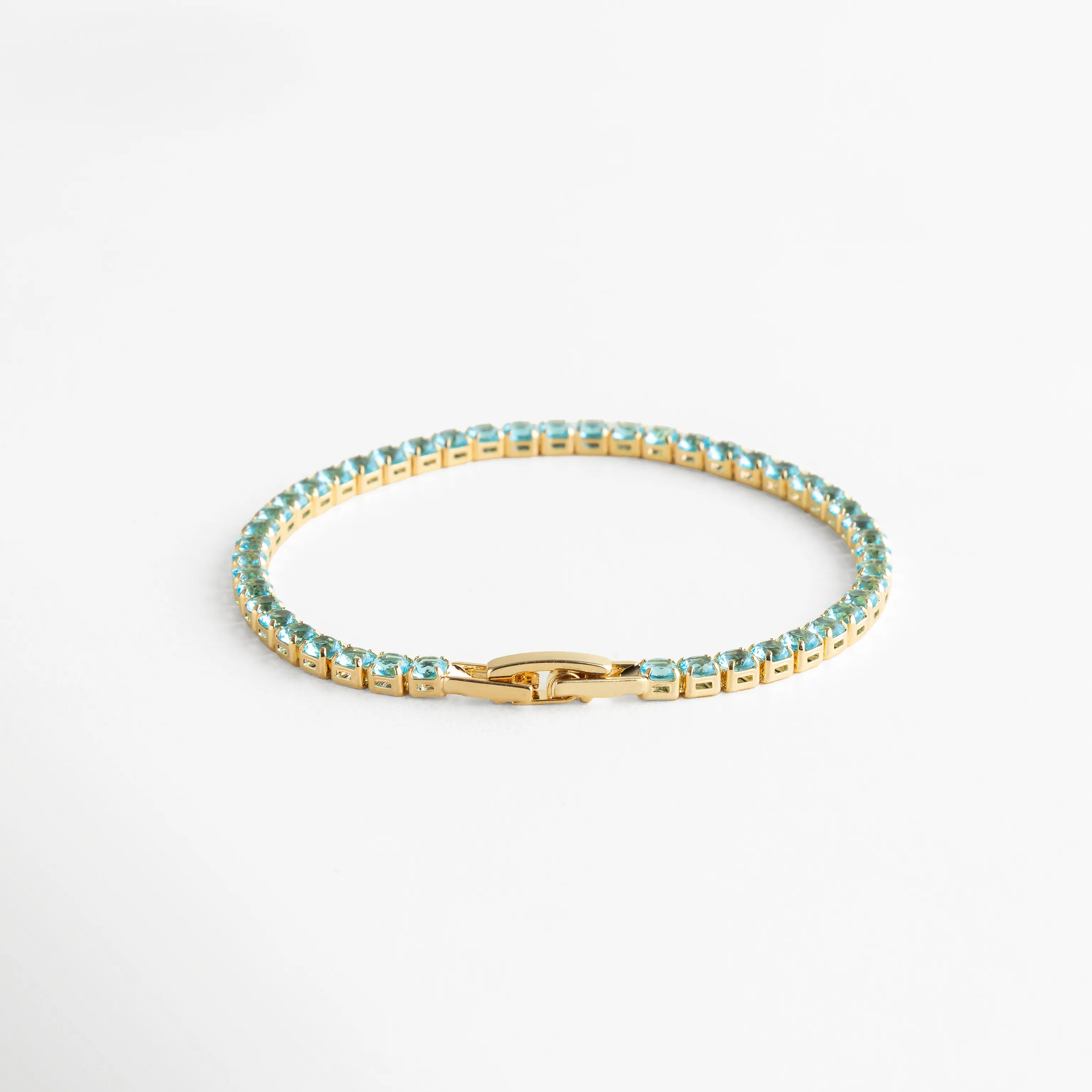 Pulsera dorada tipo tennis con cristales azules, un diseño que combina elegancia clásica con un toque moderno y luminoso.