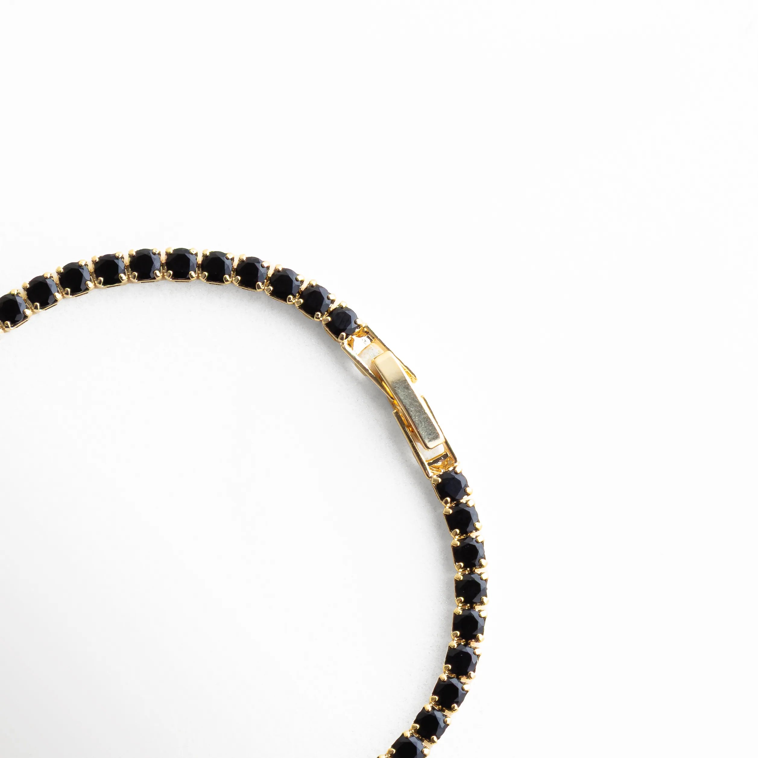 Close up de pulsera con zirconias negras y baño en oro blanco 18K, Detalle lateral de pulsera fina con piedras negras brillantes, Pulsera minimalista con incrustaciones de zirconia negra, enfoque en textura, Detalle de pulsera elegante con acabado brillante y diseño delgado, Pulsera sofisticada con zirconias negras, vista cercana del diseño