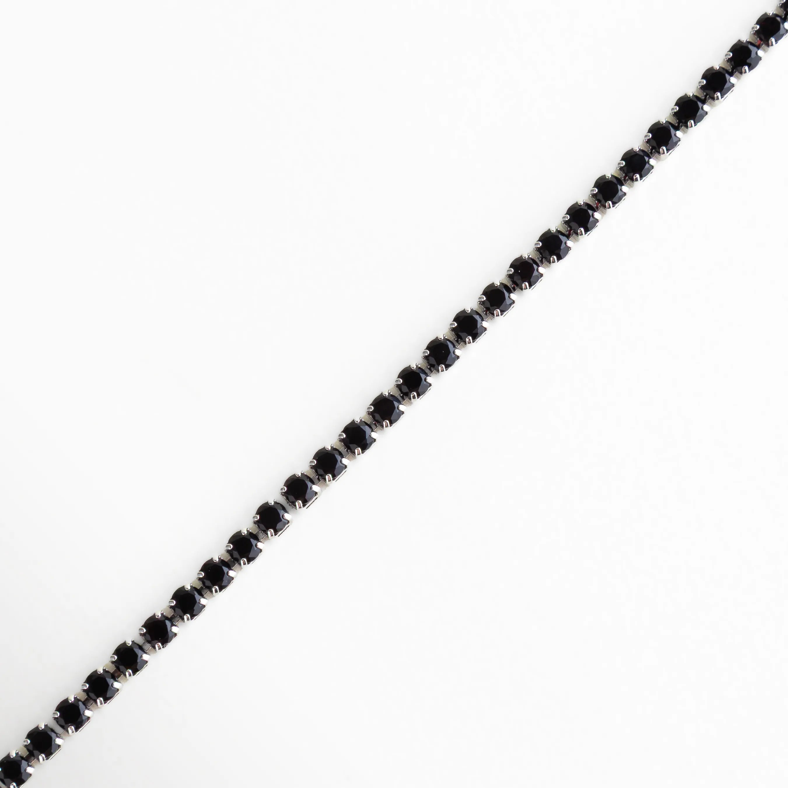 Pulsera plateada tipo tennis con cristales negros de corte redondo, un diseño elegante y atemporal.
