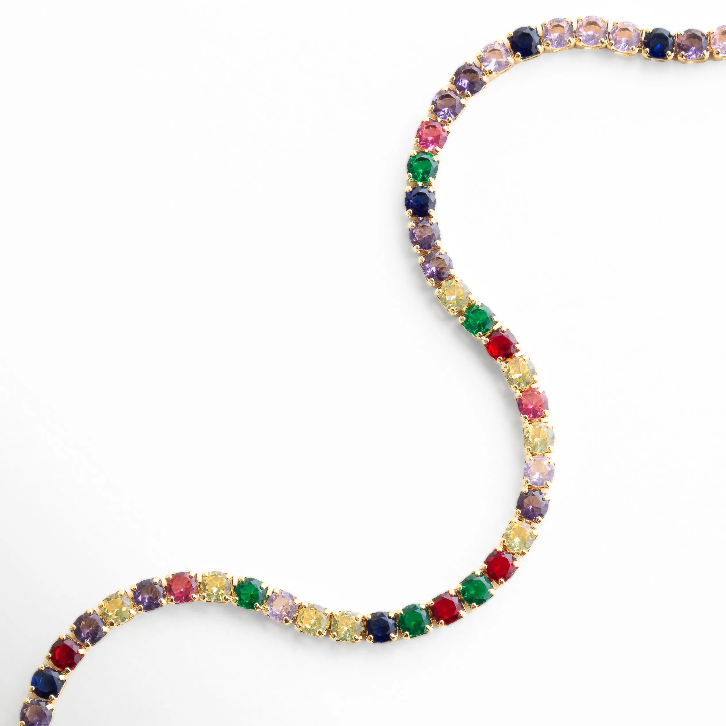 Pulsera dorada con zirconias multicolor en diseño ondulado y acabado oro 18K, Detalle de pulsera con piedras de colores vibrantes sobre base de cobre, Pulsera elegante con zirconias multicolor y brillo intenso en primer plano, Close-up de pulsera tipo tenis con mezcla de colores y acabado dorado, Pulsera fina con zirconias de colores en diseño fluido y sofisticado