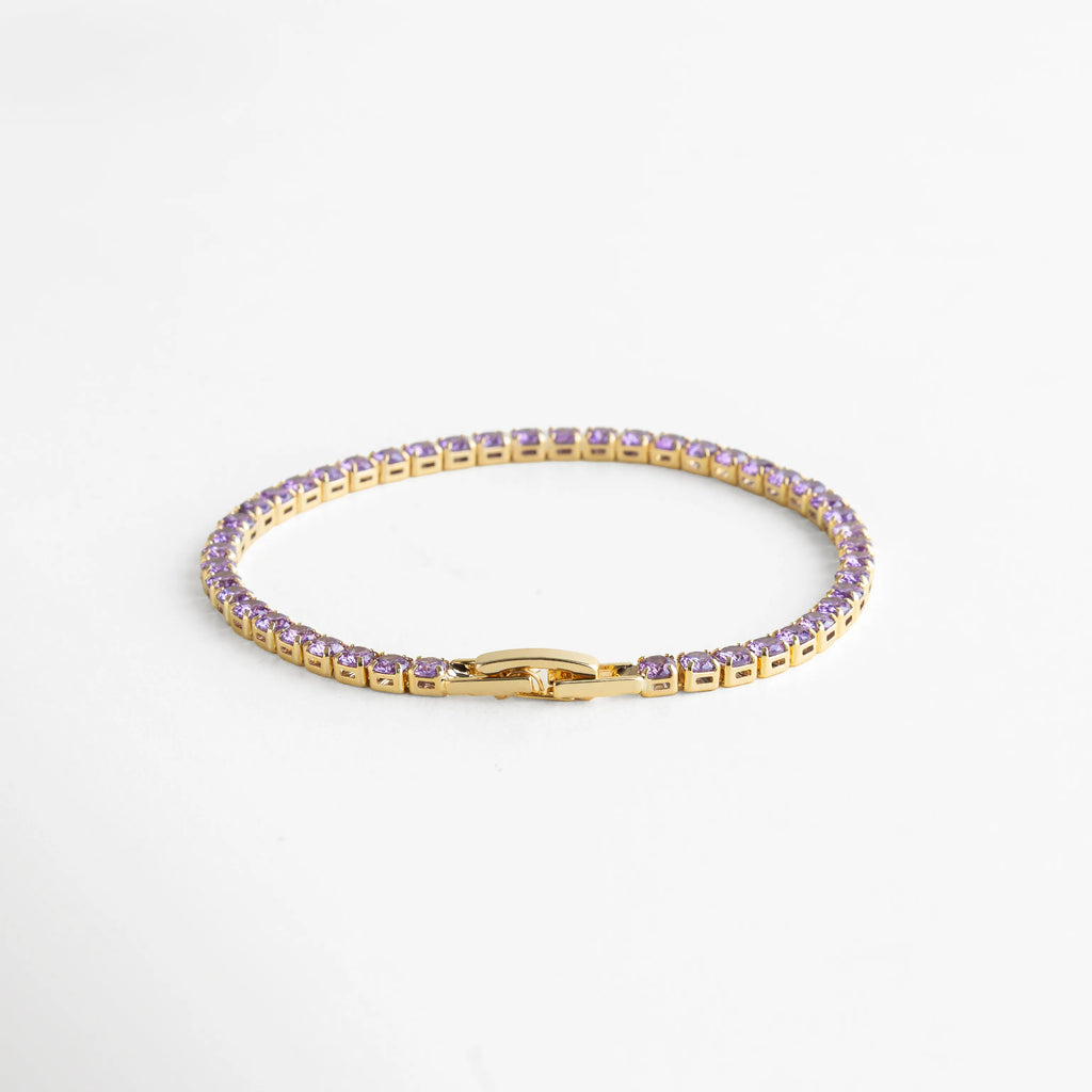 Pulsera dorada tipo tennis con cristales color amatista, ideal para un look delicado y sofisticado.