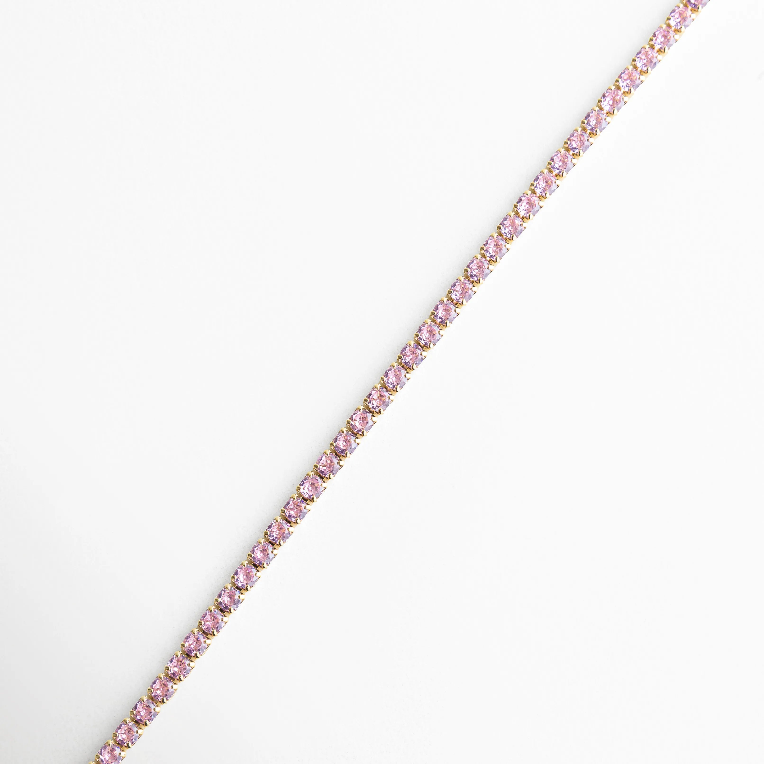 Pulsera tipo tenis multicolor en línea recta con zirconias y acabado oro 18K, Pulsera delgada con piedras de colores alineadas sobre fondo claro, Vista lateral de pulsera con zirconias multicolor en diseño continuo, Pulsera elegante de 18 cm con brillo uniforme y acabado dorado, Diseño minimalista de pulsera con zirconias arcoíris en base de cobre