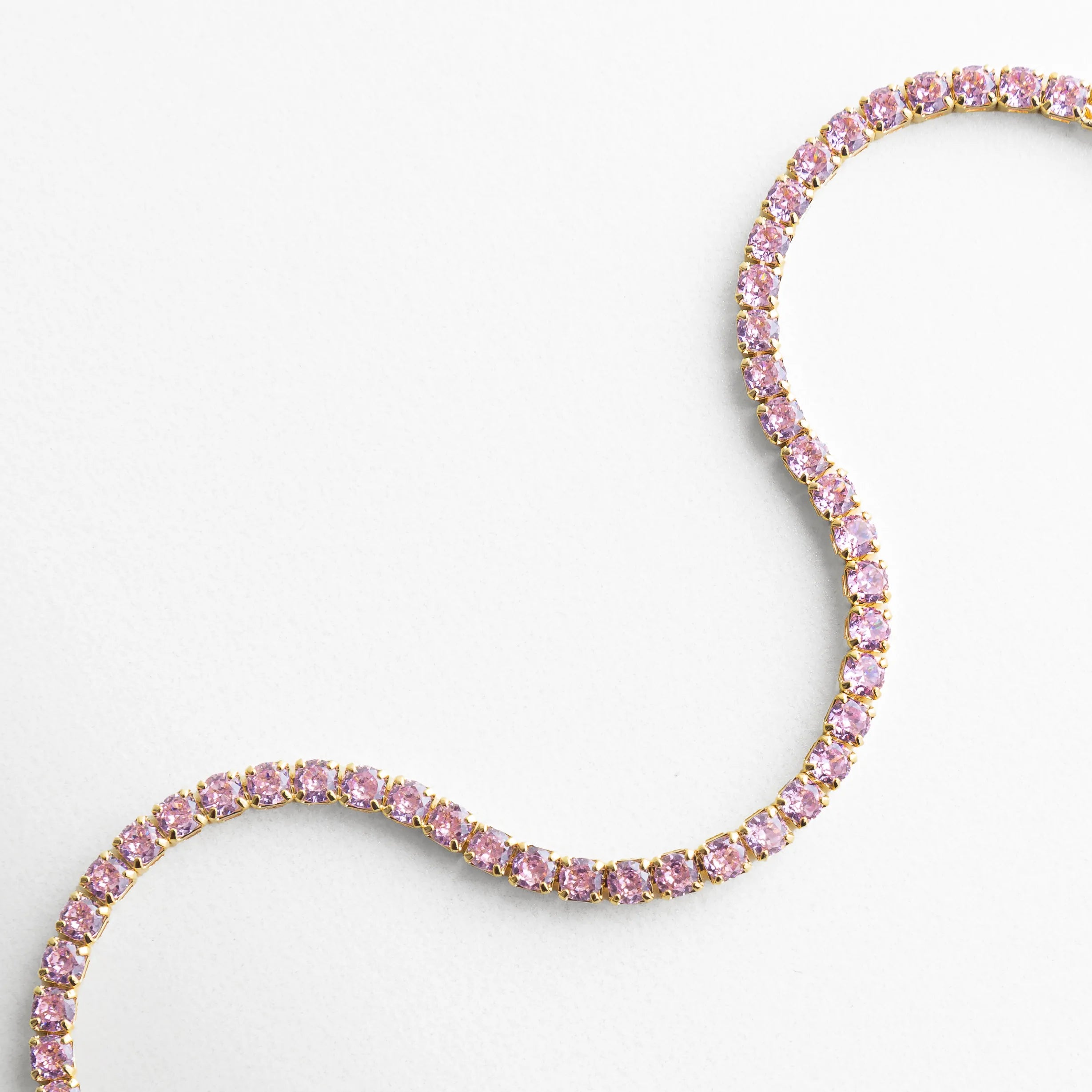 Pulsera dorada con zirconias multicolor en diseño ondulado y acabado oro 18K, Pulsera tipo tenis con zirconias de colores sobre base de cobre en primer plano, Detalle de pulsera elegante con piedras brillantes multicolor y acabado dorado, Pulsera fina con zirconias arcoíris en diseño flexible y sofisticado, Close-up de pulsera dorada con zirconias multicolor de alto brillo
