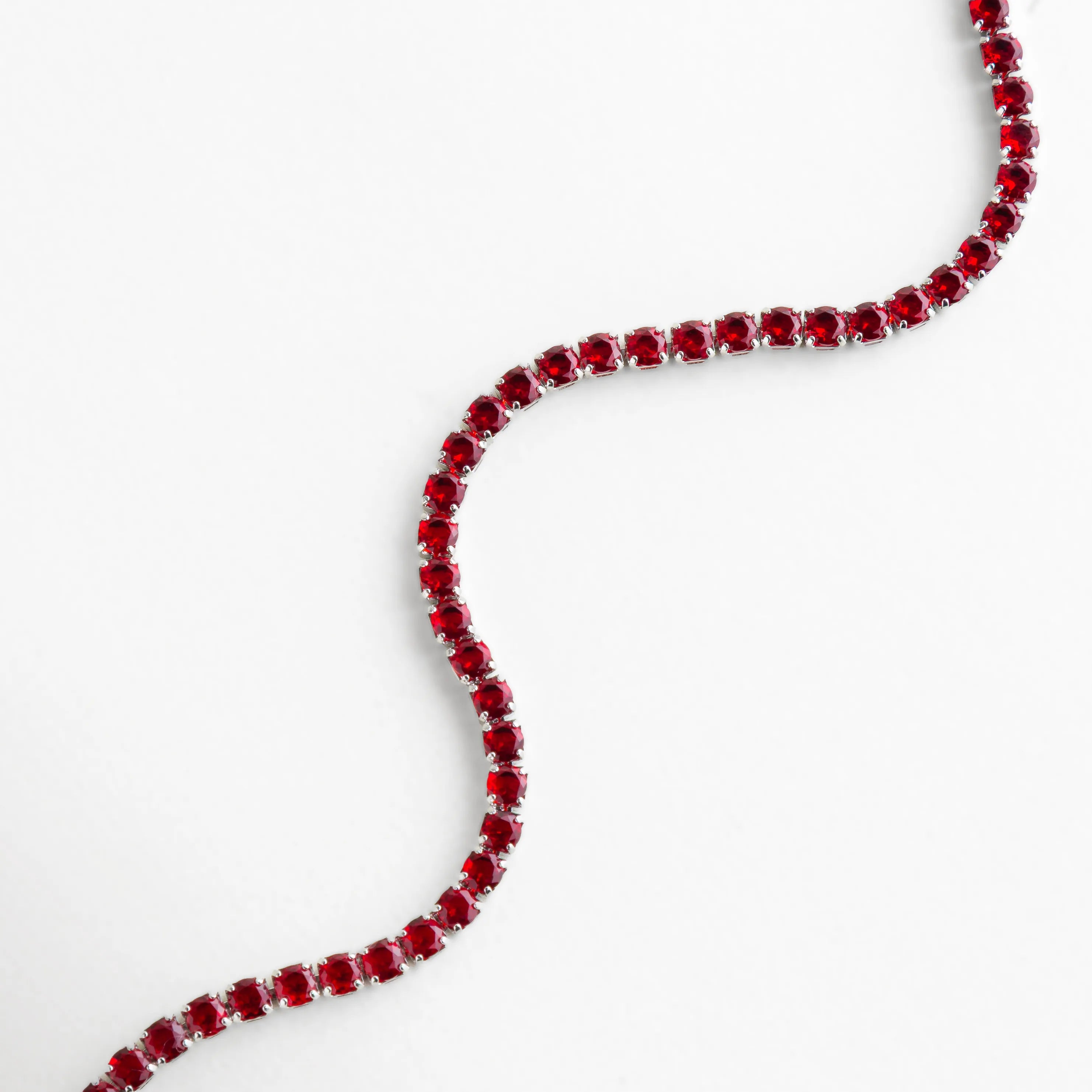 Pulsera de cristales rojos dispuestos en una línea continua, reflejando luz con cada movimiento.