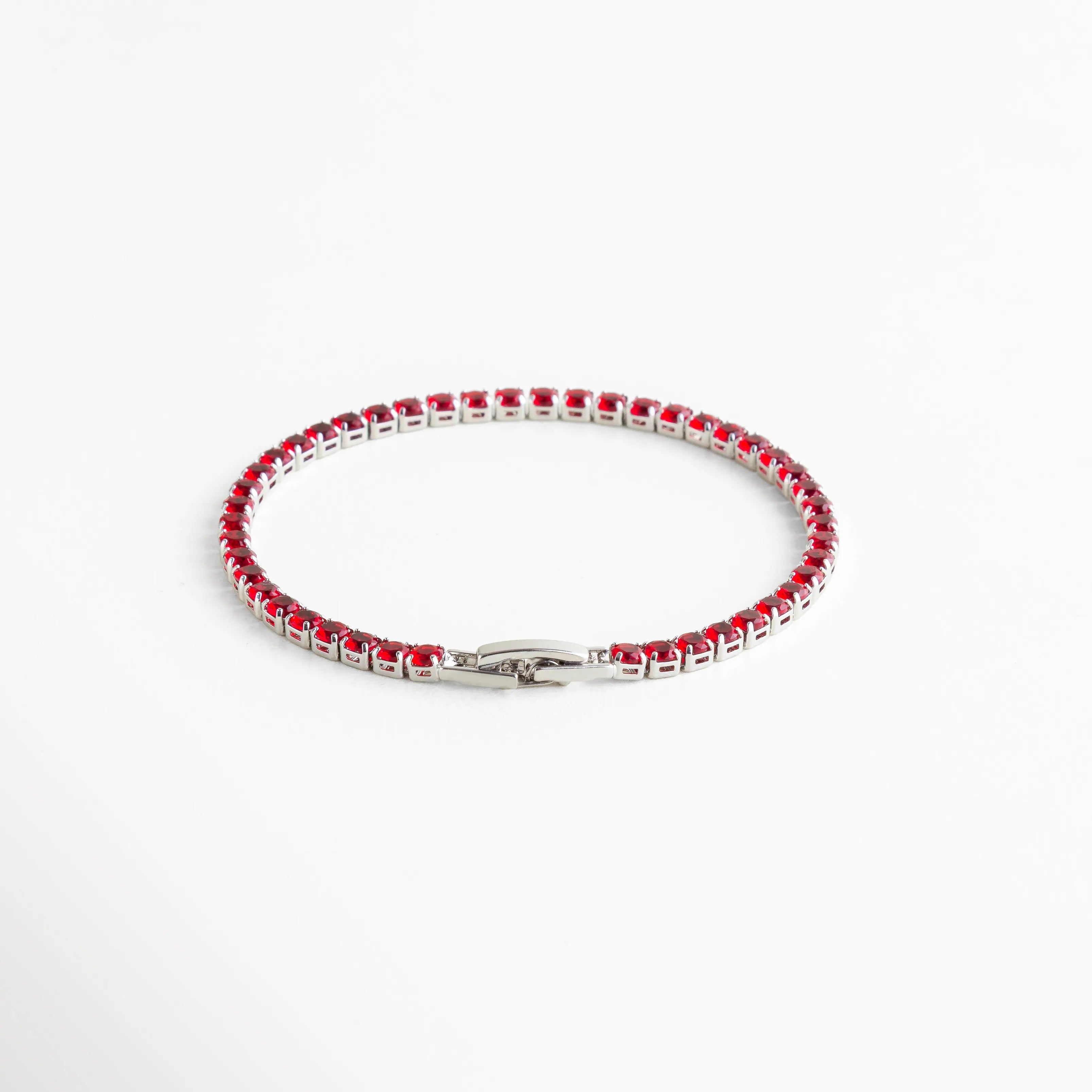 Pulsera plateada tipo tennis con cristales rojos, un diseño clásico que aporta un toque vibrante y sofisticado.