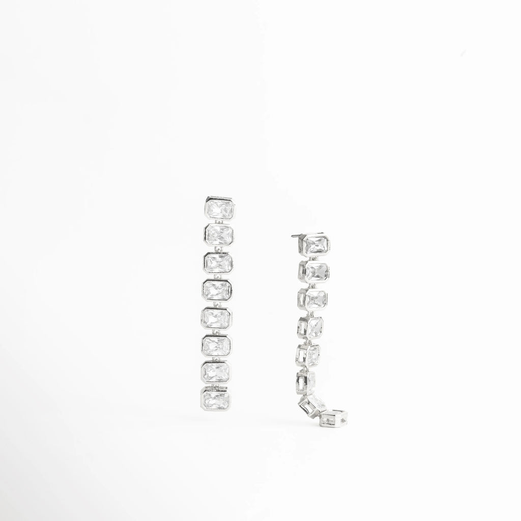 aretes plateados vista diagonal, aretes curvos con piedras, joyería elegante con brillo, aretes modernos diseño, accesorios plateados mujer, aretes sofisticados largos, joyería luminosa plateada, aretes estilizados