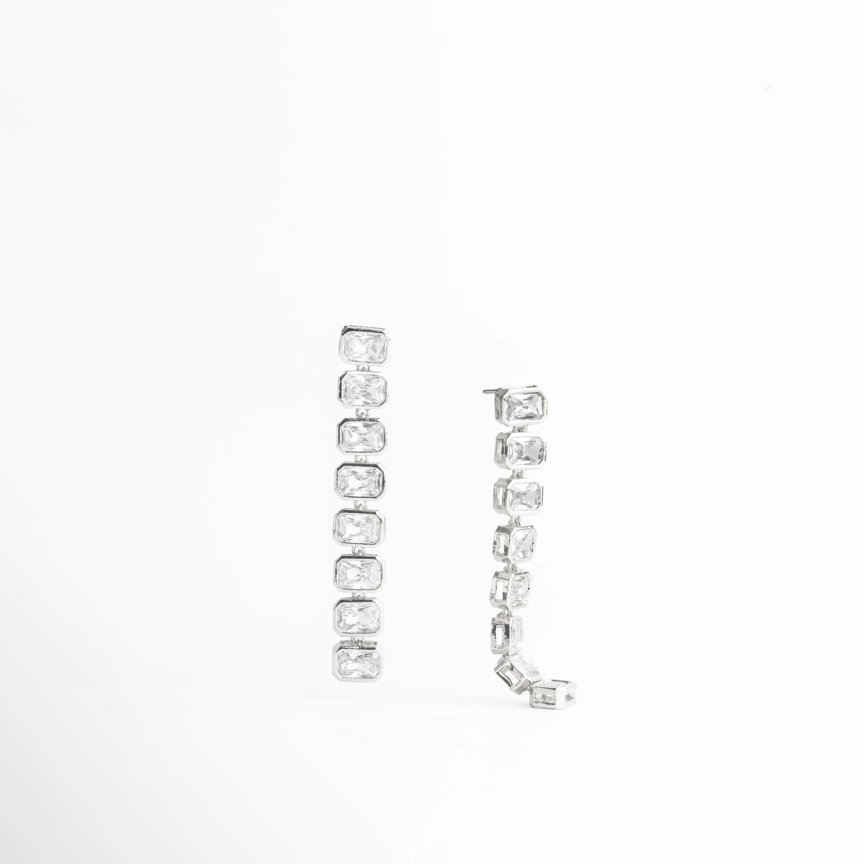 aretes plateados vista diagonal, aretes curvos con piedras, joyería elegante con brillo, aretes modernos diseño, accesorios plateados mujer, aretes sofisticados largos, joyería luminosa plateada, aretes estilizados