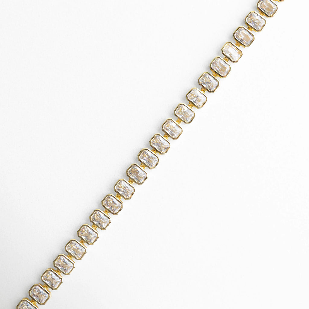 Pulsera dorada extendida con zirconias alineadas y brillo intenso, Vista lineal de pulsera tipo tenis con piedras brillantes, Pulsera dorada en línea con diseño continuo de zirconias, Detalle extendido de pulsera con acabado en oro 18K, Vista de pulsera con patrón uniforme de zirconias brillantes