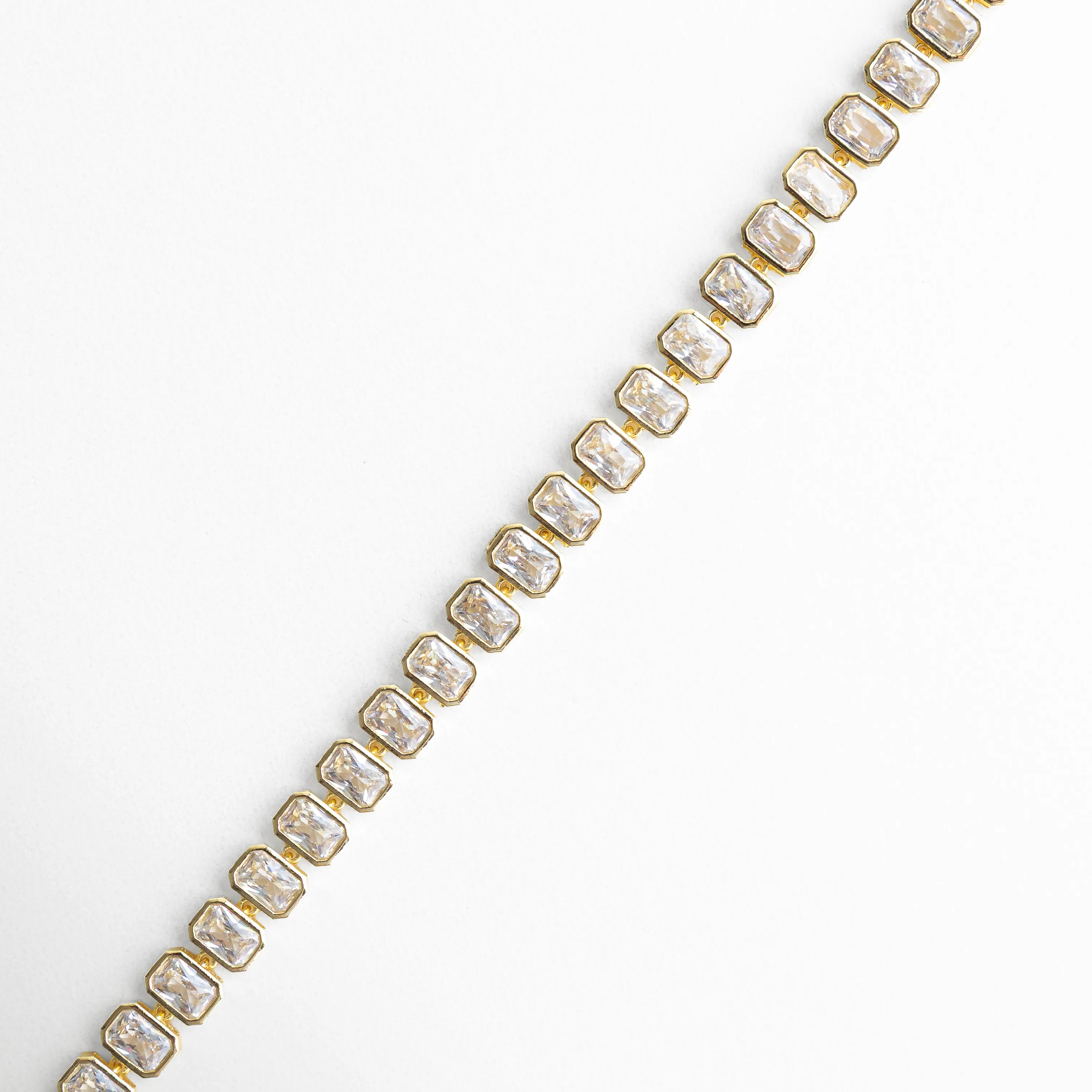 Pulsera dorada extendida con zirconias alineadas y brillo intenso, Vista lineal de pulsera tipo tenis con piedras brillantes, Pulsera dorada en línea con diseño continuo de zirconias, Detalle extendido de pulsera con acabado en oro 18K, Vista de pulsera con patrón uniforme de zirconias brillantes