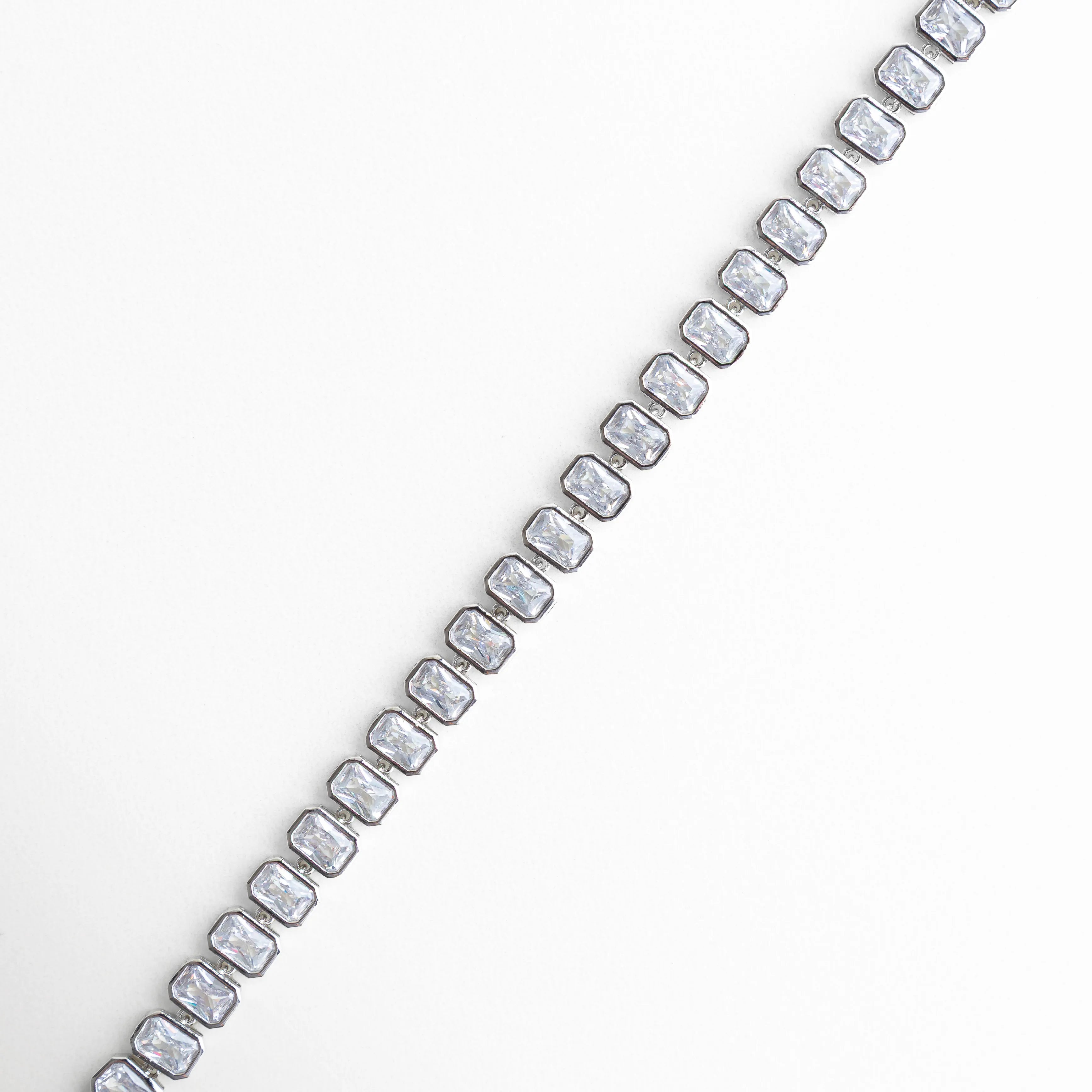 Vista lateral de pulsera con zirconias en línea continua, Perfil de pulsera tipo tenis con piedras brillantes y diseño fino, Pulsera vista de lado con estructura elegante y zirconias, Lateral de pulsera plateada con incrustaciones brillantes, Detalle lateral con alineación perfecta de zirconias