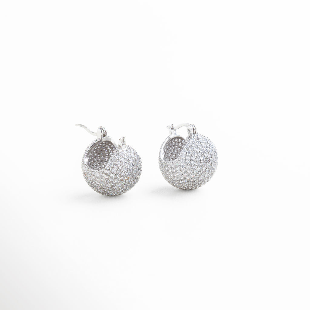 Perfil de pendiente con zirconias en recubrimiento plata 18K, Aretes pequeños con brillo sutil vistos en ángulo lateral, Diseño compacto y brillante de pendientes en plata con zirconias, Vista lateral de pendientes con piedras zirconias