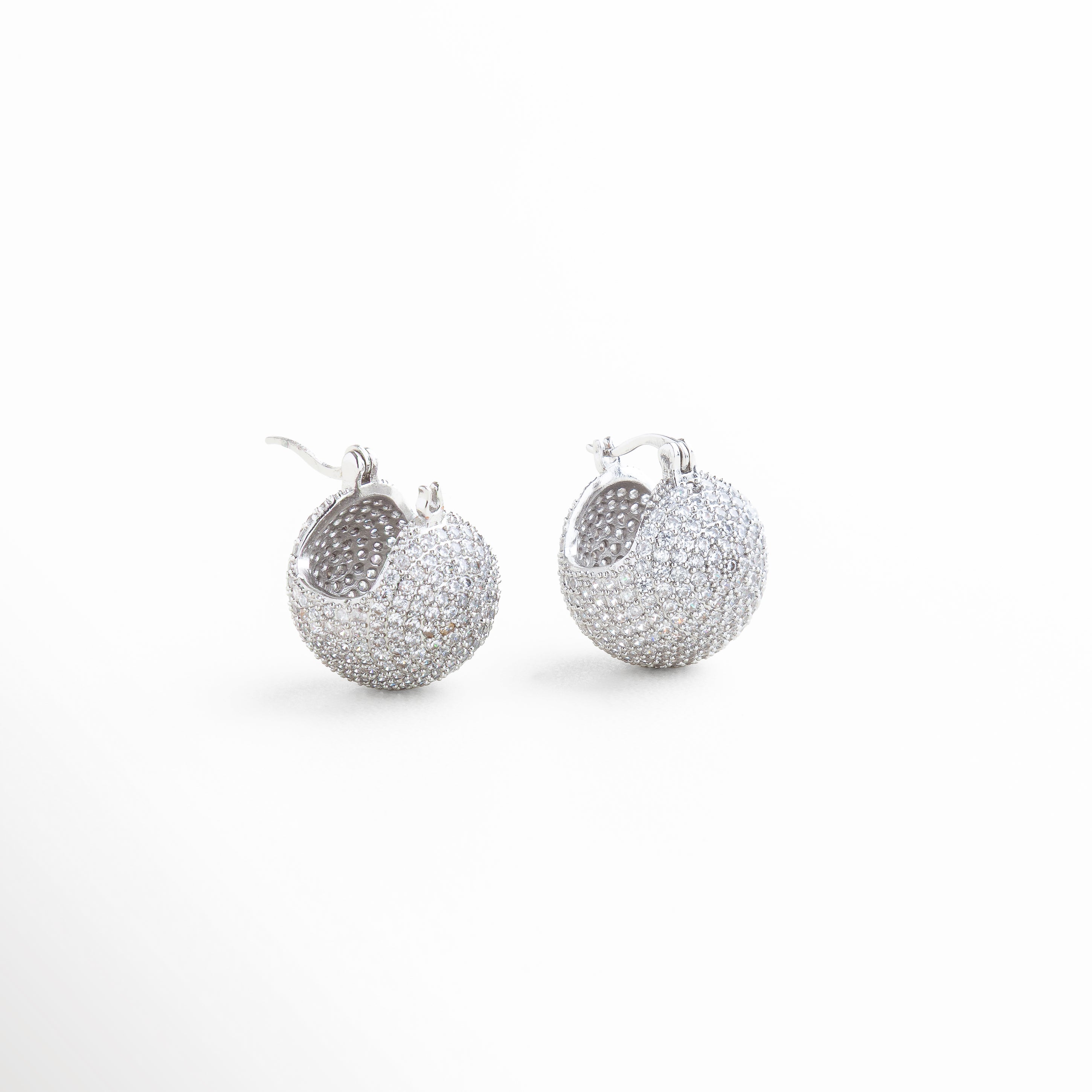 Perfil de pendiente con zirconias en recubrimiento plata 18K, Aretes pequeños con brillo sutil vistos en ángulo lateral, Diseño compacto y brillante de pendientes en plata con zirconias, Vista lateral de pendientes con piedras zirconias