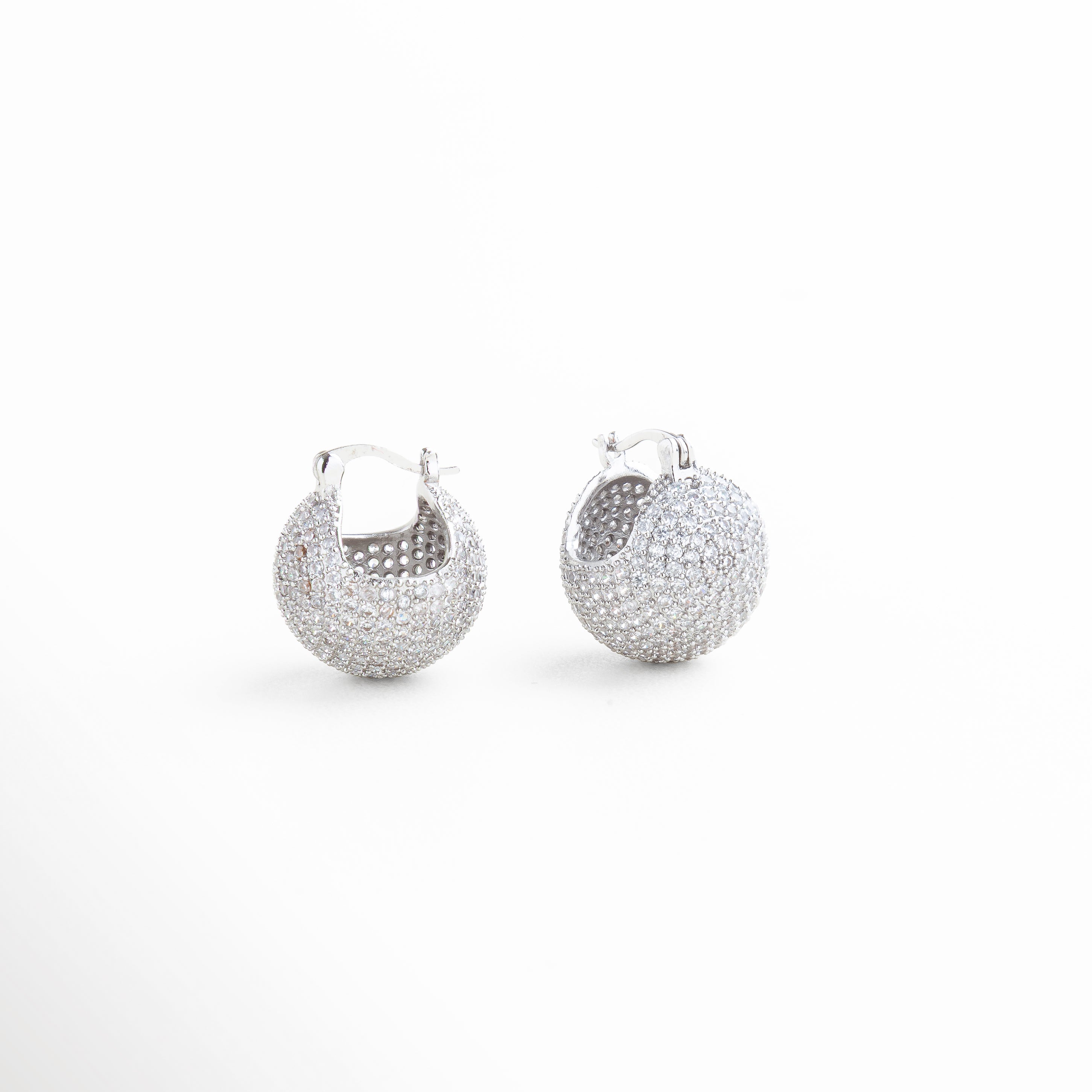 Primer plano de pendiente plateado con zirconias que reflejan luz, Detalle de incrustaciones de zirconias en pendiente de chapa de plata, Brillo intenso de zirconias engastadas en pendientes de plata 18K, Close-up de zirconias en pendiente pequeño y elegante