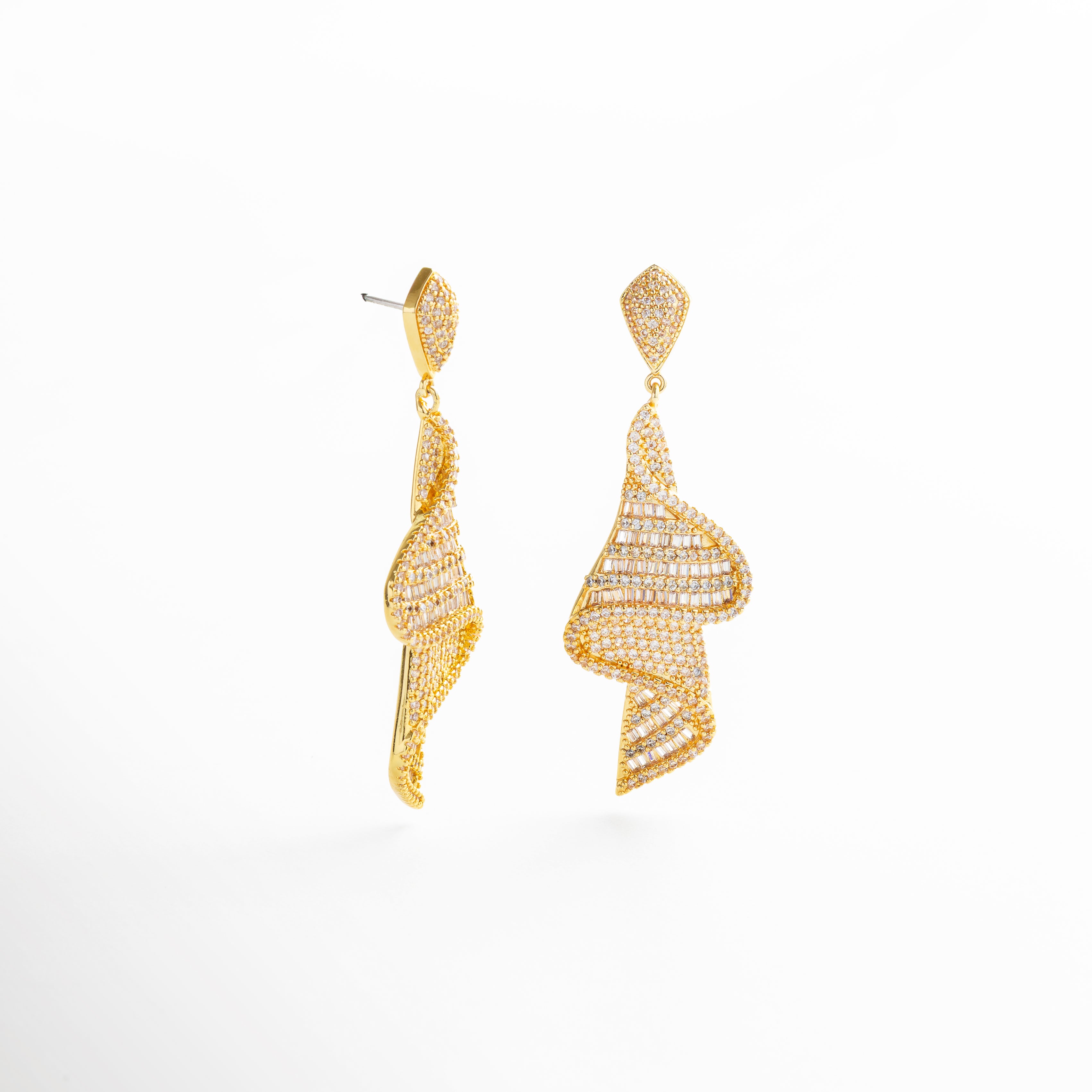 incrustaciones de zirconia en acabado dorado, textura brillante del baño en chapa de oro 14K, detalle del engarzado de zirconias en cada arete, reflejo de luz en la superficie facetada de la pieza, acabado pulido y bordes definidos en diseño glam