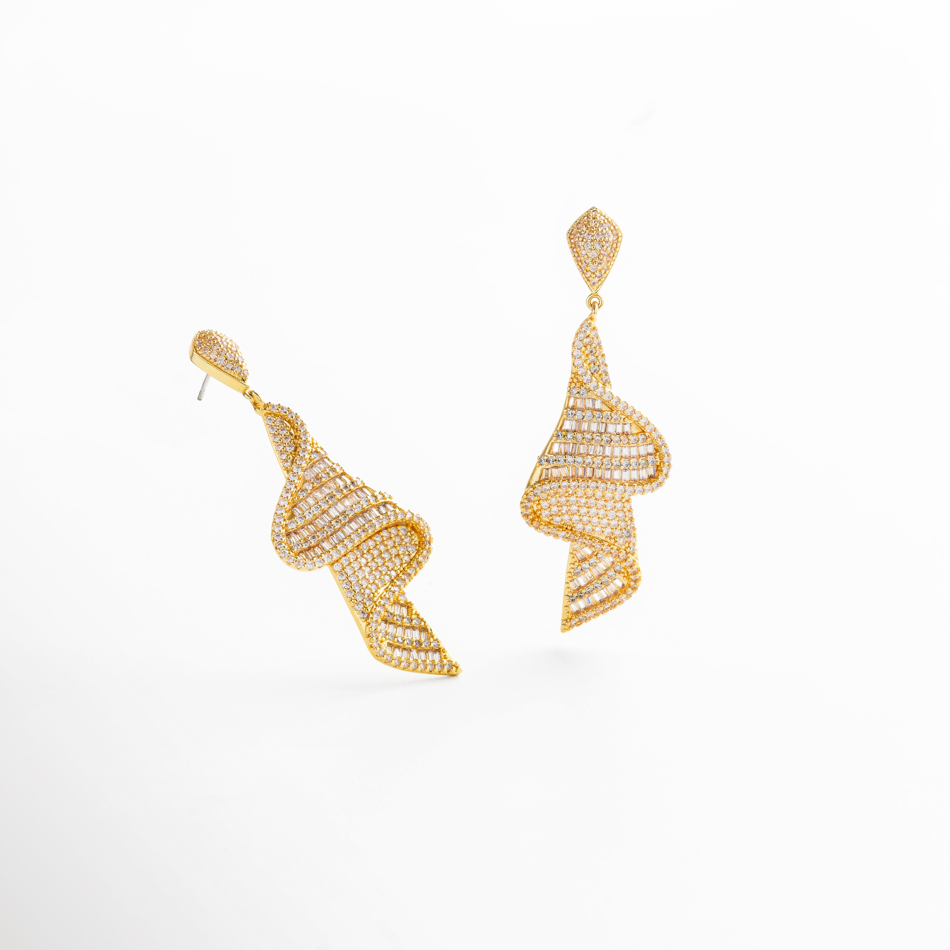 proporción real de los aretes de 6.3 cm de largo, escala visual en comparación con el rostro, tamaño alargado con diseño llamativo, largo visible de los aretes dorados con zirconias, relación entre ancho y longitud de la pieza