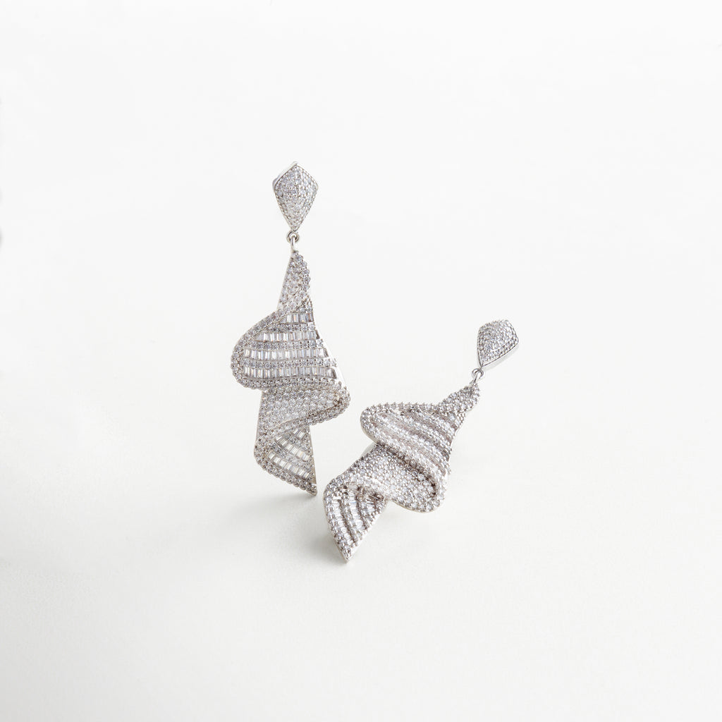 Detalle de zirconias en aretes dorados con acabado fino, Close-up de incrustaciones brillantes en diseño glamoroso, Textura brillante y detalles de lujo en aretes con baño de oro, Primer plano de aretes con piedras y diseño elegante