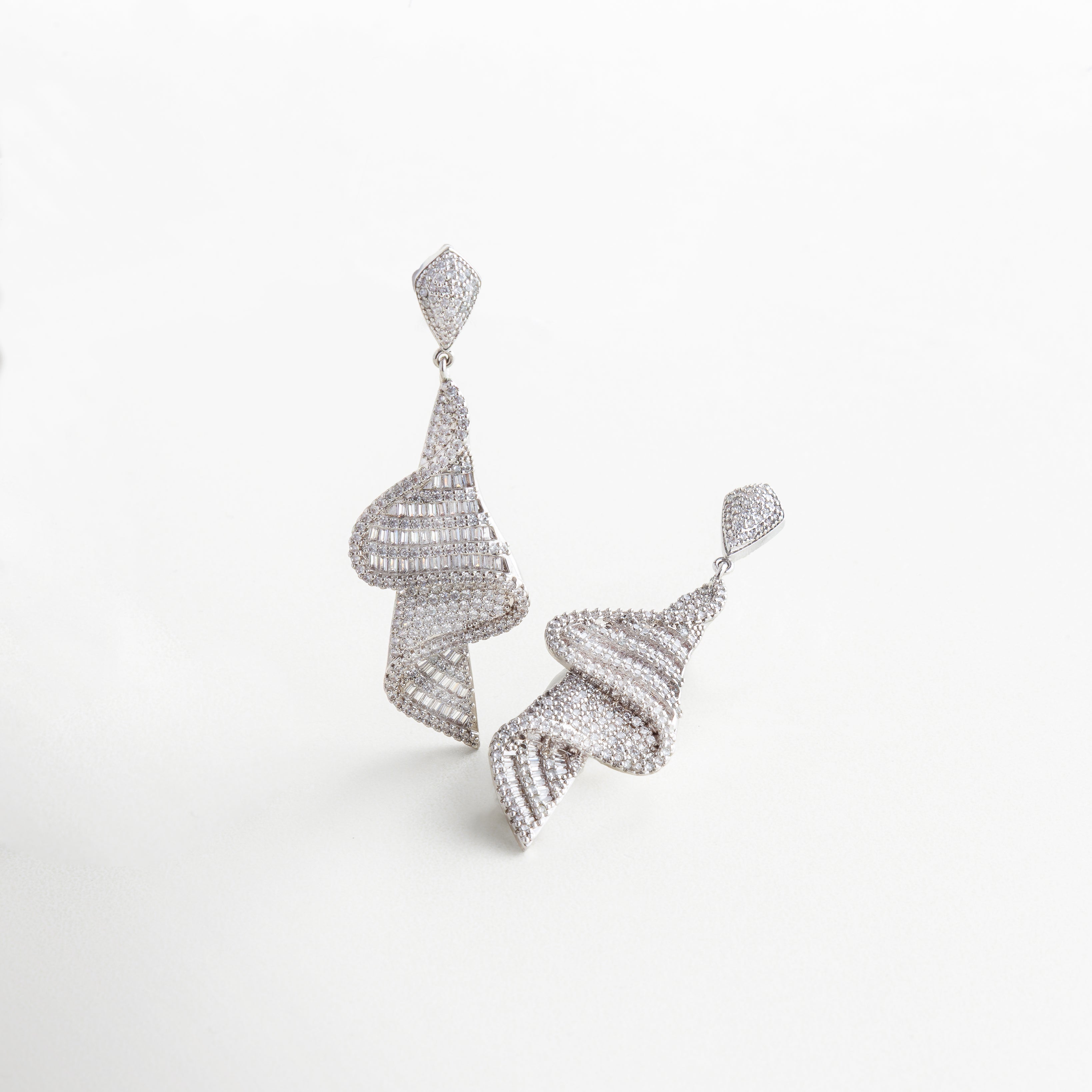 Detalle de zirconias en aretes dorados con acabado fino, Close-up de incrustaciones brillantes en diseño glamoroso, Textura brillante y detalles de lujo en aretes con baño de oro, Primer plano de aretes con piedras y diseño elegante