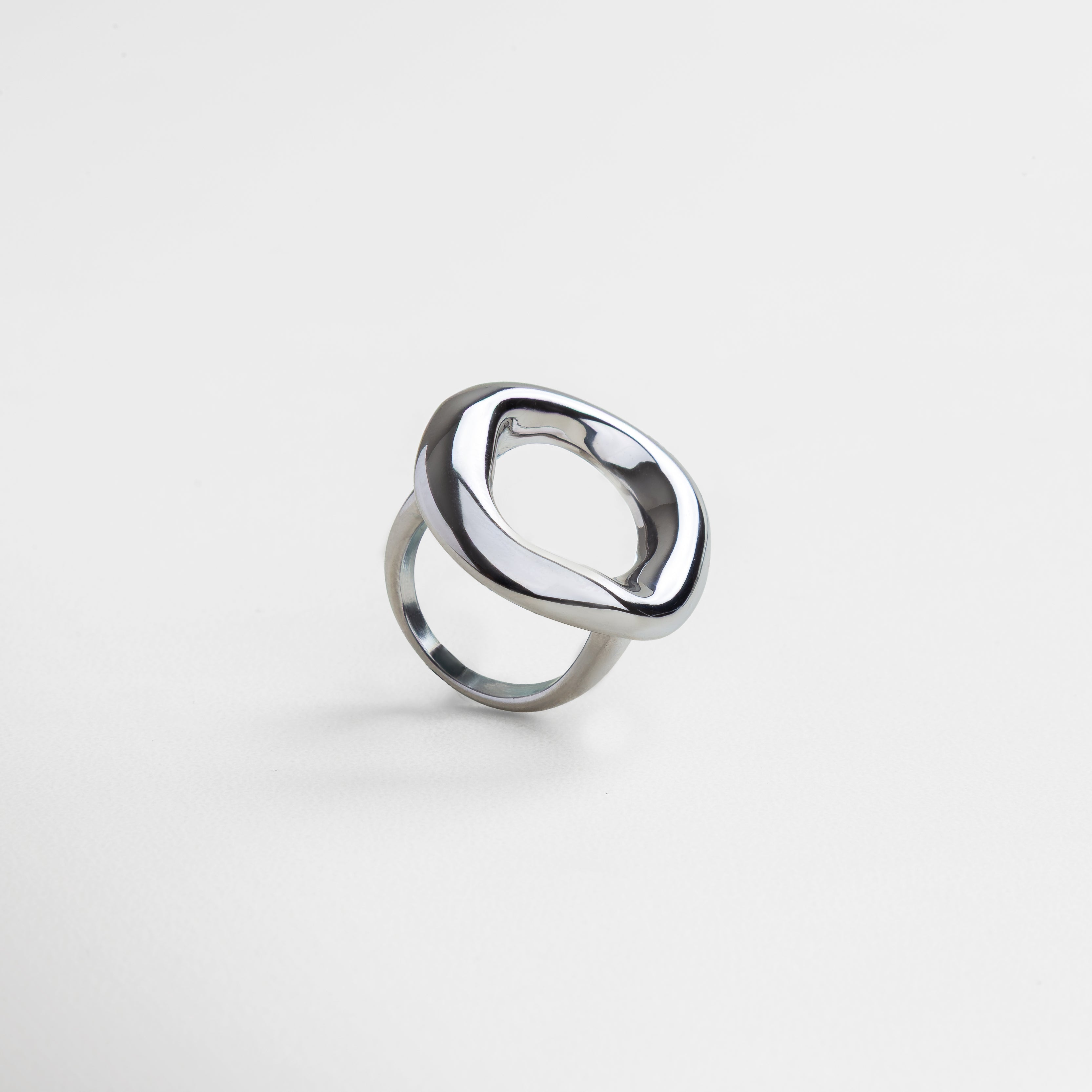 Anillo plateado con diseño curvo visto de perfil, Silueta ancha y elegante del Anillo Donna en ángulo, Joya contemporánea en acero inoxidable vista en diagonal, Diseño bold del anillo en perspectiva lateral