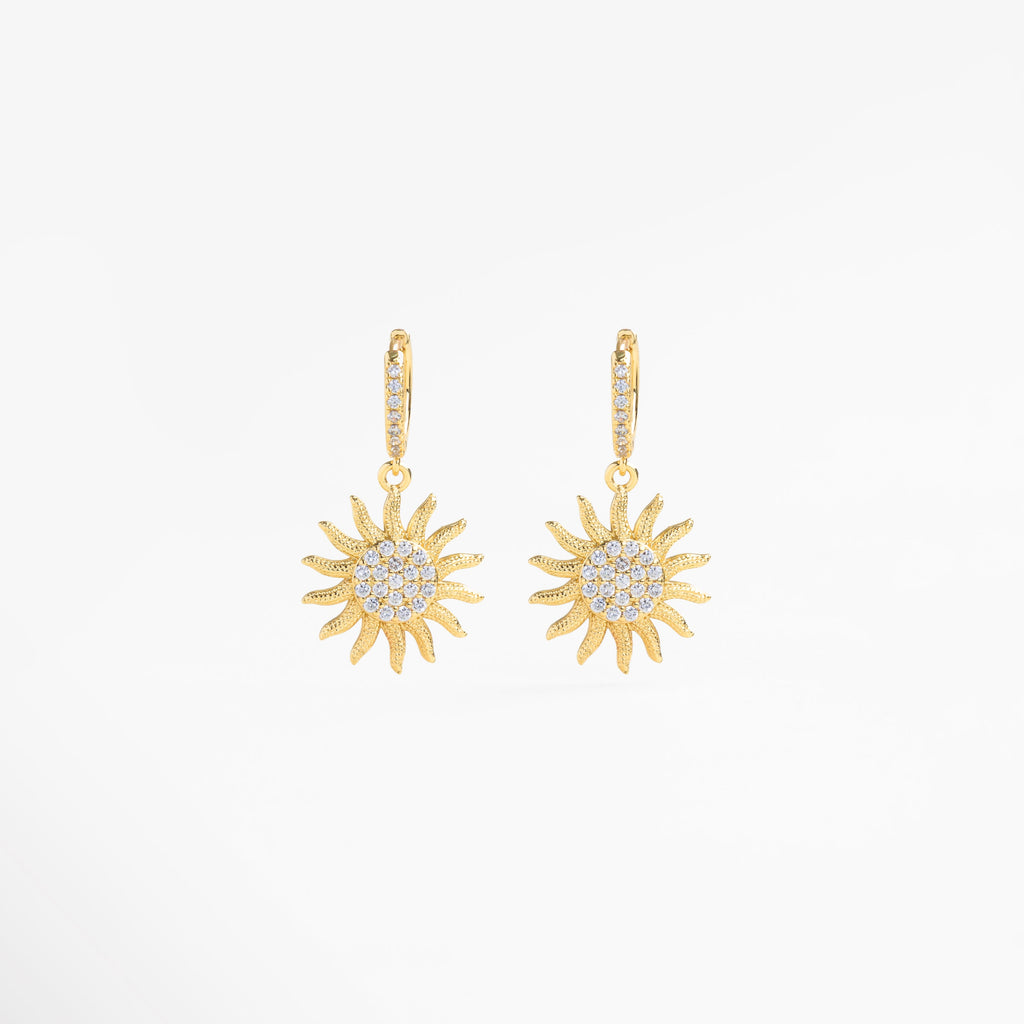 Aretes colgantes dorados vistos en ángulo con brillo de zirconias, Detalle lateral de pendientes largos en oro con piedras, Aretes de chapa de oro vistos de perfil con destellos, Vista lateral de aretes sunrise con forma elegante, Pendientes curvos dorados con movimiento y luz