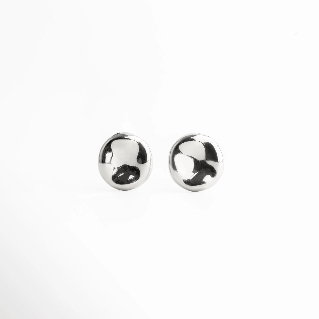 aretes plateados vista frontal, aretes redondos plateados, joyería minimal mujer, aretes pequeños elegantes, accesorios femeninos plateados, joyería plateada moderna, aretes pulidos clásicos, aretes chic diarios