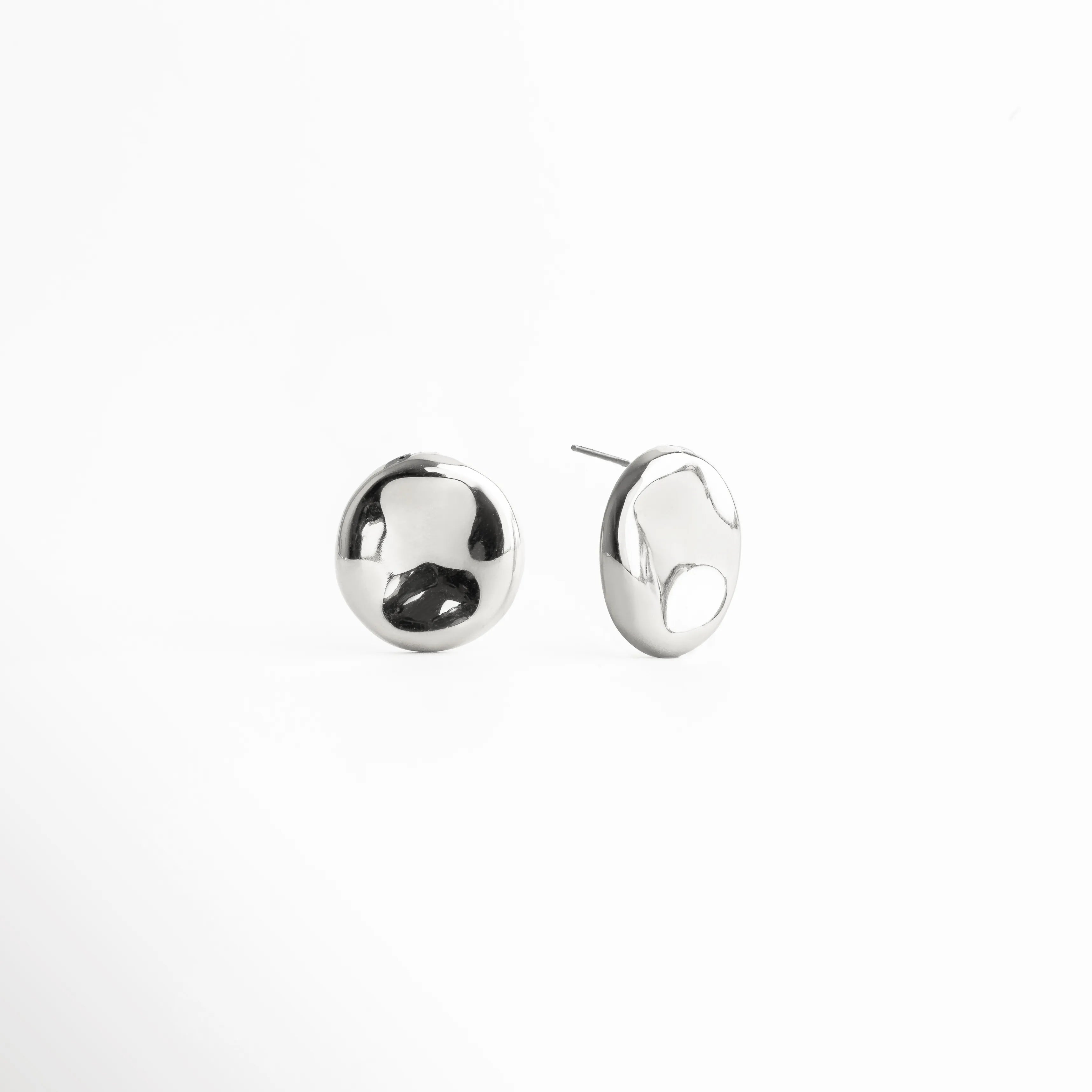 aretes plateados pulidos, aretes tipo botón, joyería plateada minimalista, aretes modernos mujer, aretes redondos elegantes, accesorios plateados chic, aretes básicos sofisticados, joyería contemporánea