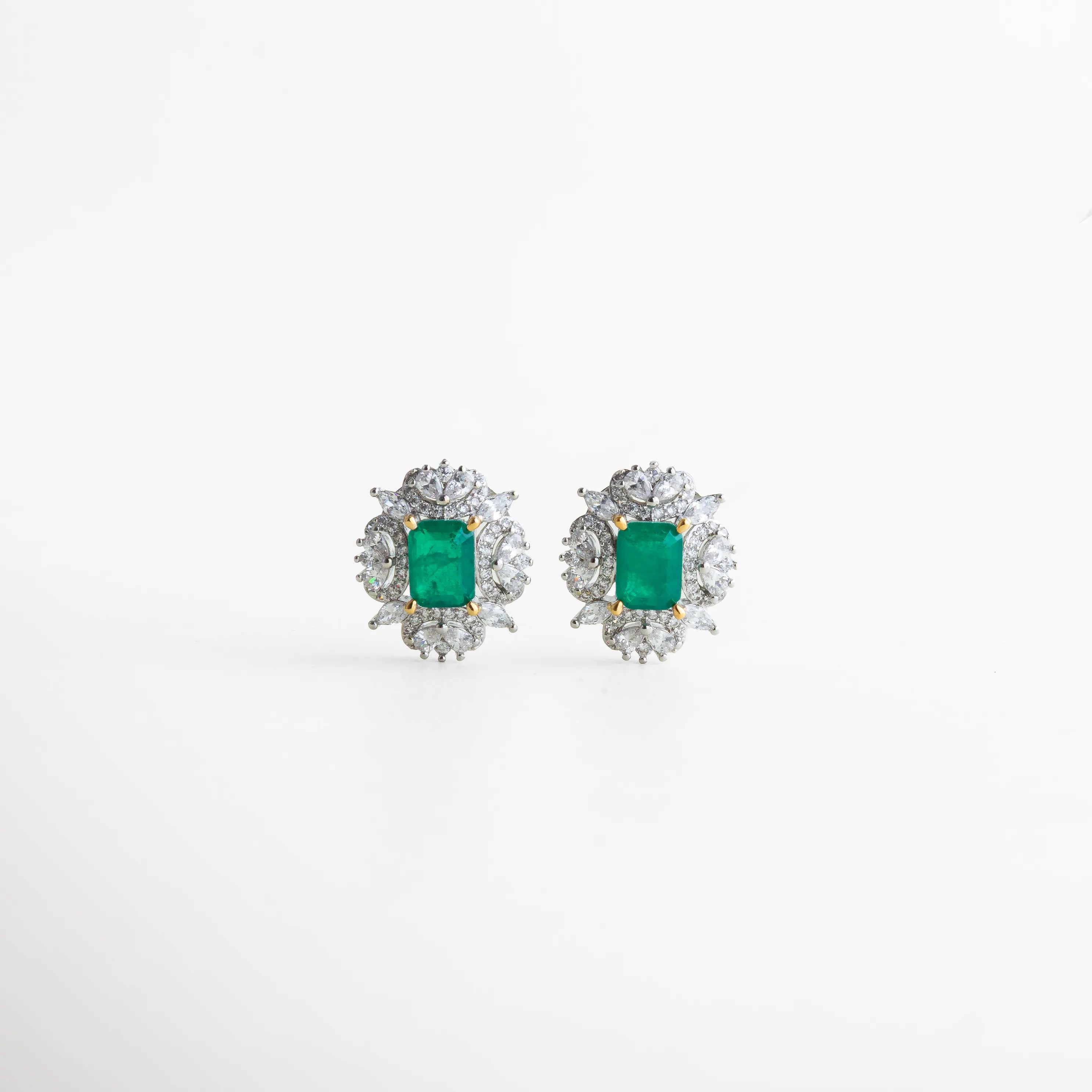 Par de aretes plateados con piedras centrales color esmeralda de forma rectangular y marco de zirconias en distintos tamaños. Su brillo equilibrado aporta un toque de glamour refinado, ideal para elevar cualquier atuendo formal.