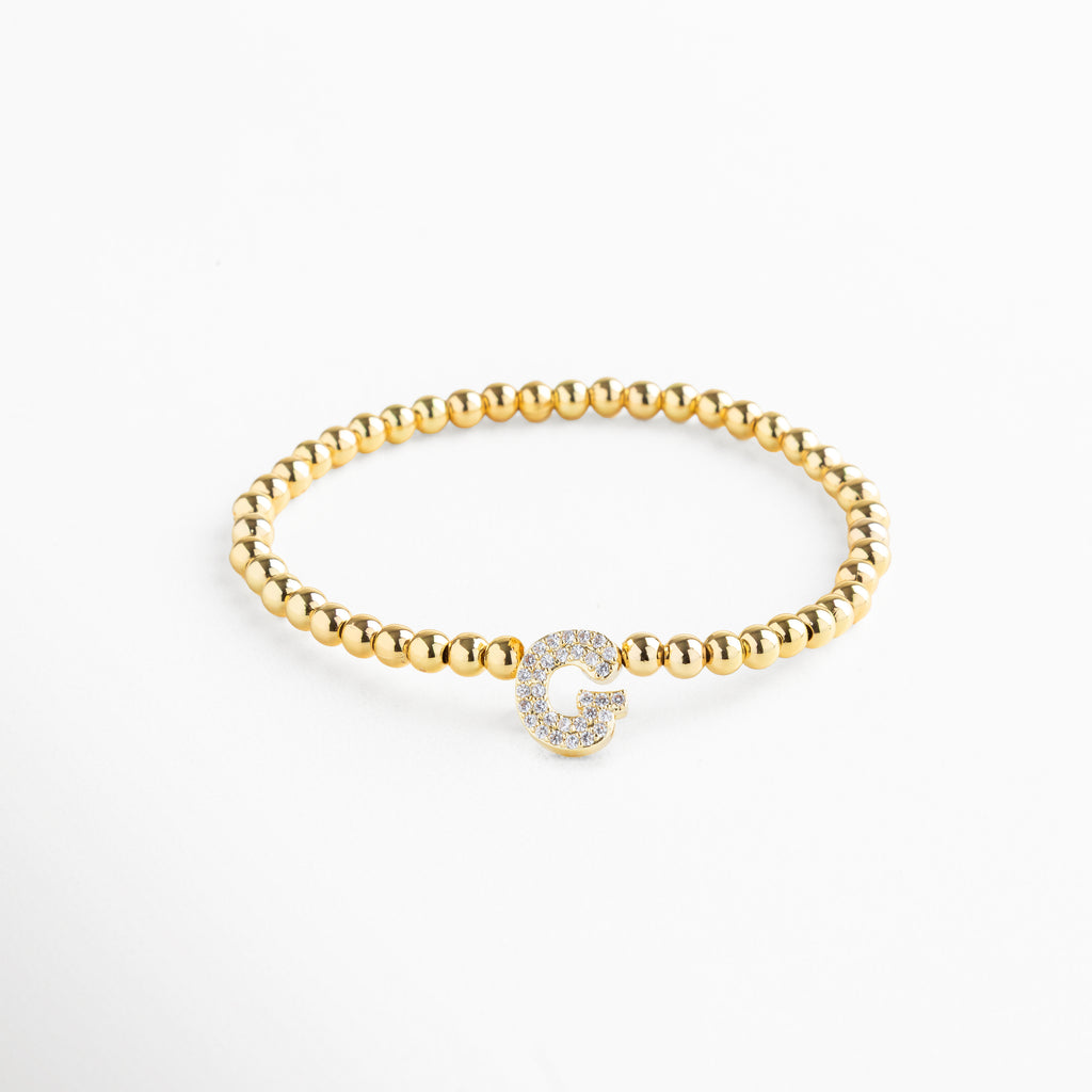 Pulsera elástica de cobre con recubrimiento enchapado en oro 18K e incrustaciones de zirconias, diseño de cuentas doradas con dije en forma de letra G personalizada, joya delicada y versátil de 1 x 0.7 cm ideal para uso diario.