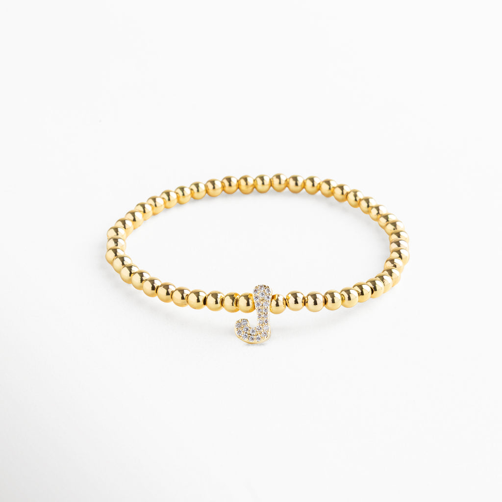 Pulsera elástica de cobre con recubrimiento enchapado en oro 18K e incrustaciones de zirconias, diseño de cuentas doradas con dije en forma de letra J personalizada, joya delicada y versátil de 1 x 0.7 cm ideal para uso diario.