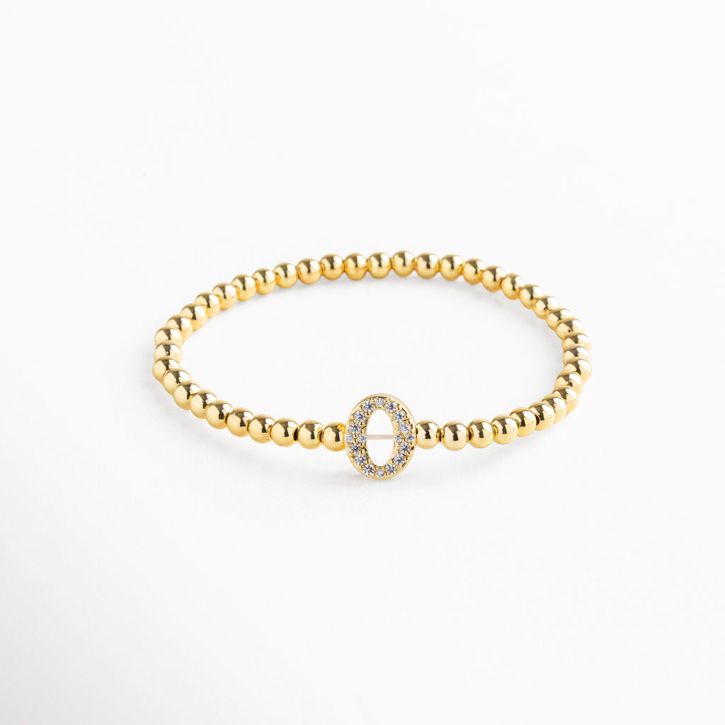 Pulsera elástica de cobre con recubrimiento enchapado en oro 18K e incrustaciones de zirconias, diseño de cuentas doradas con dije en forma de letra O personalizada, joya delicada y versátil de 1 x 0.7 cm ideal para uso diario.