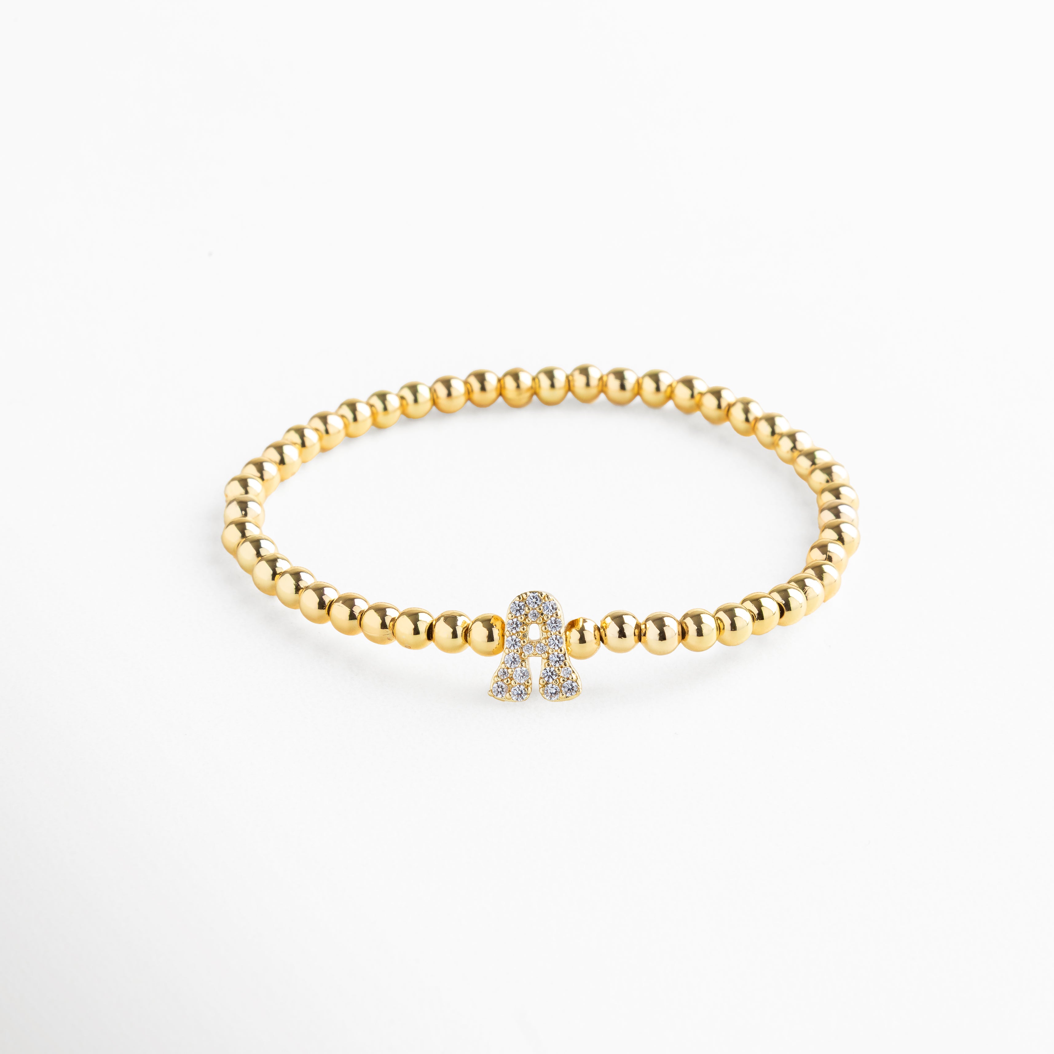 Pulsera elástica de cobre con recubrimiento enchapado en oro 18K e incrustaciones de zirconias, diseño de cuentas doradas con dije en forma de letra A personalizada, joya delicada y versátil de 1 x 0.7 cm ideal para uso diario.