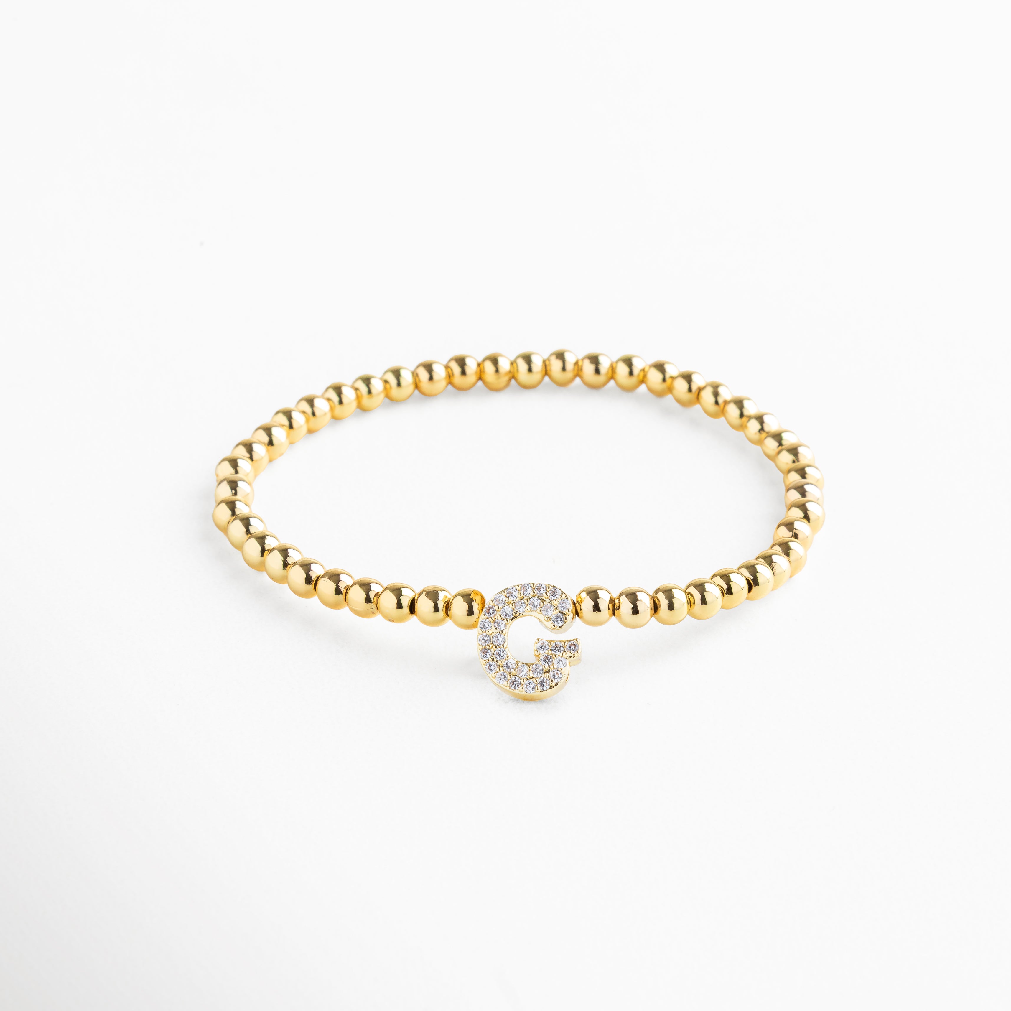 Pulsera elástica de cobre con recubrimiento enchapado en oro 18K e incrustaciones de zirconias, diseño de cuentas doradas con dije en forma de letra G personalizada, joya delicada y versátil de 1 x 0.7 cm ideal para uso diario.