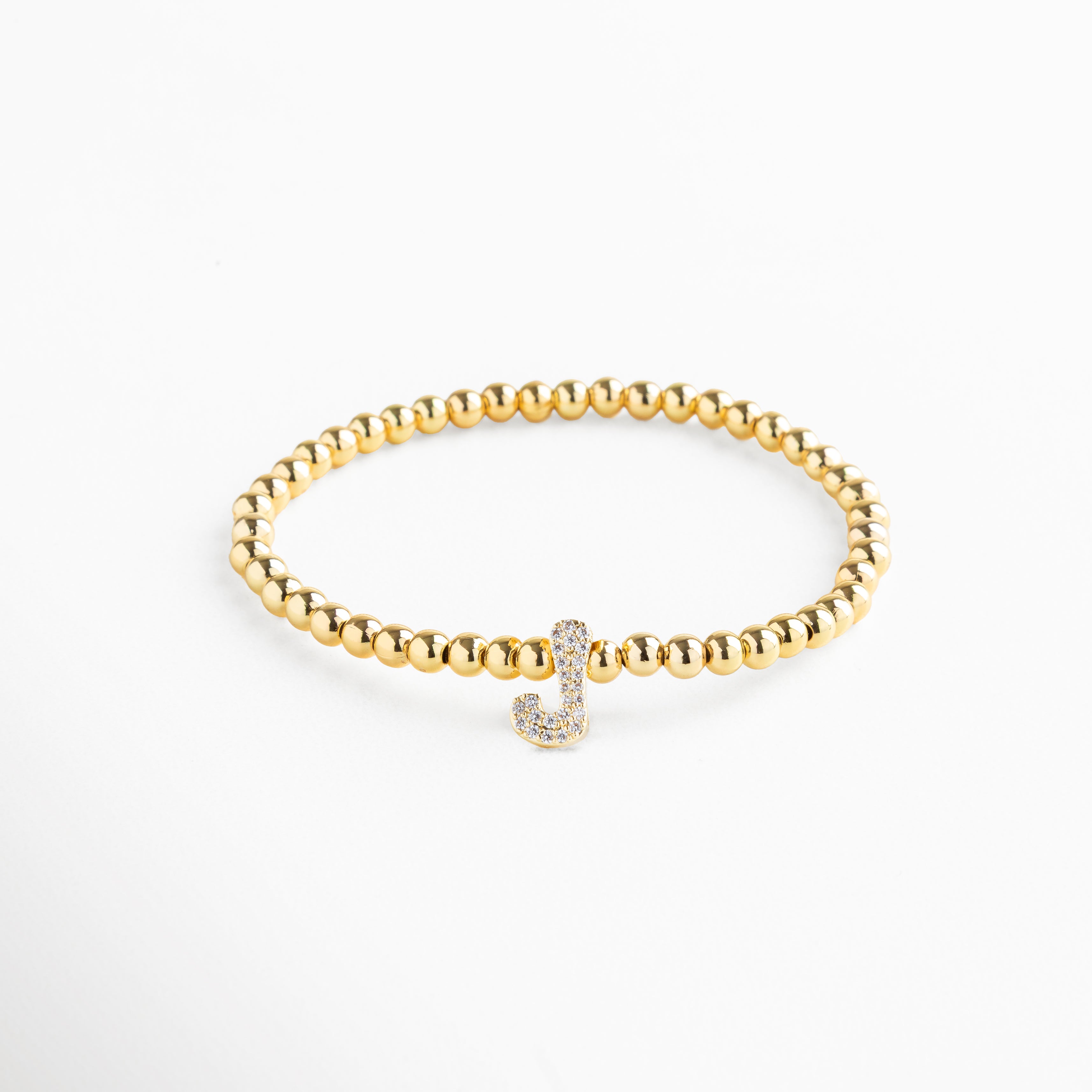 Pulsera elástica de cobre con recubrimiento enchapado en oro 18K e incrustaciones de zirconias, diseño de cuentas doradas con dije en forma de letra J personalizada, joya delicada y versátil de 1 x 0.7 cm ideal para uso diario.
