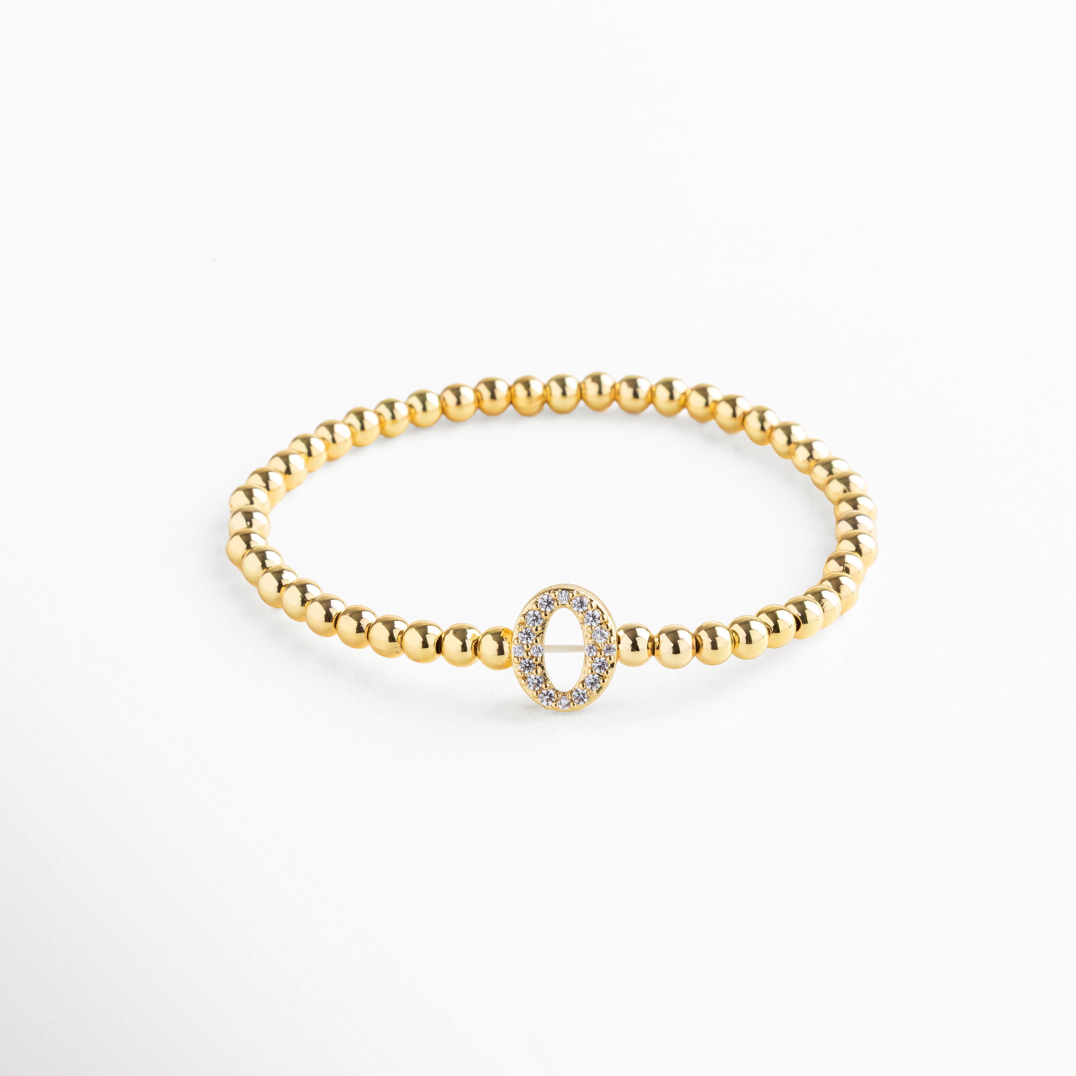 Pulsera elástica de cobre con recubrimiento enchapado en oro 18K e incrustaciones de zirconias, diseño de cuentas doradas con dije en forma de letra O personalizada, joya delicada y versátil de 1 x 0.7 cm ideal para uso diario.