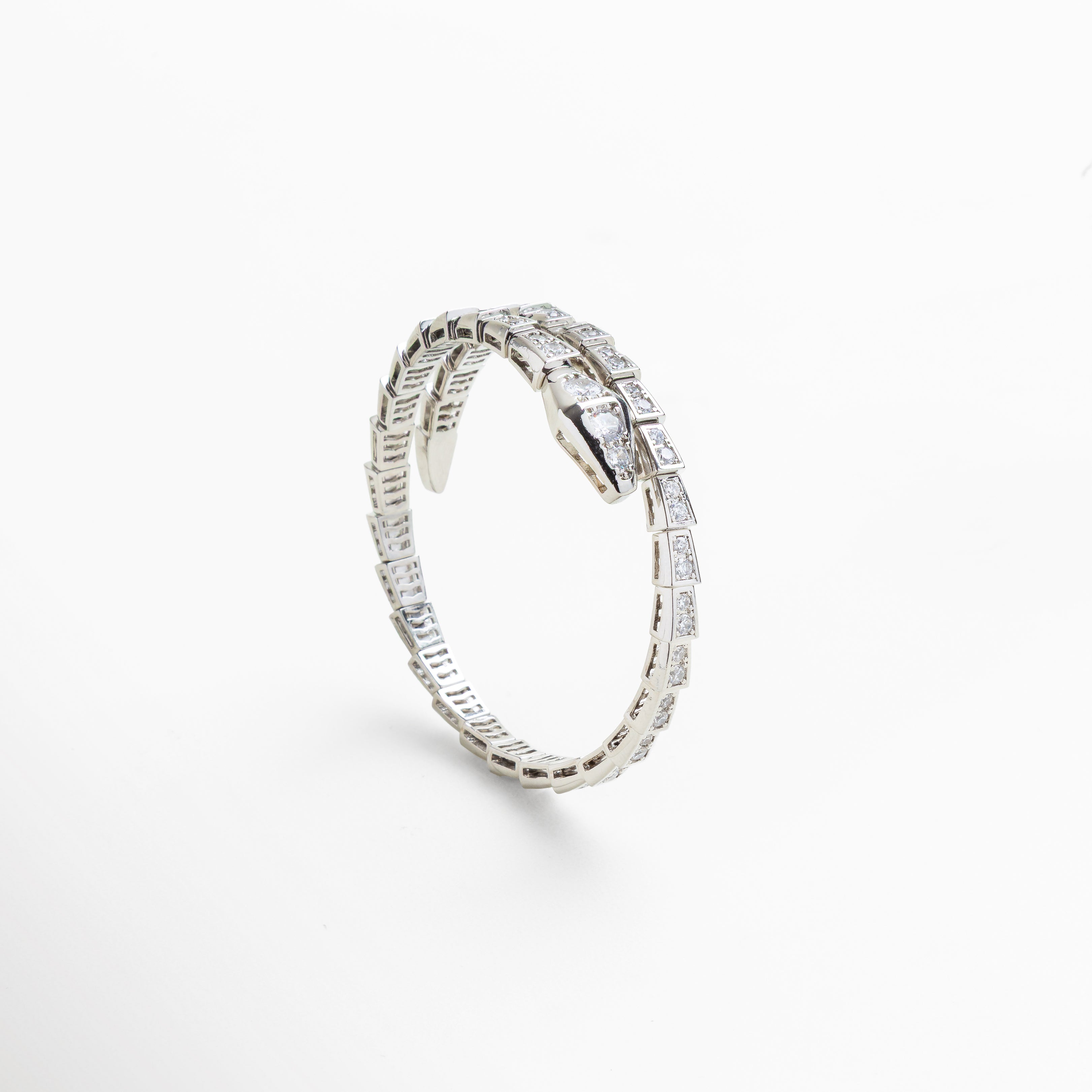 Acercamiento a la estructura flexible y articulada de la pulsera, Diseño envolvente que se adapta a la muñeca con estilo, Brillo intenso de las zirconias cúbicas incrustadas en escamas, Cierre oculto con forma de serpiente, elegante y seguro, Grosor y ancho del brazalete visible en primer plano