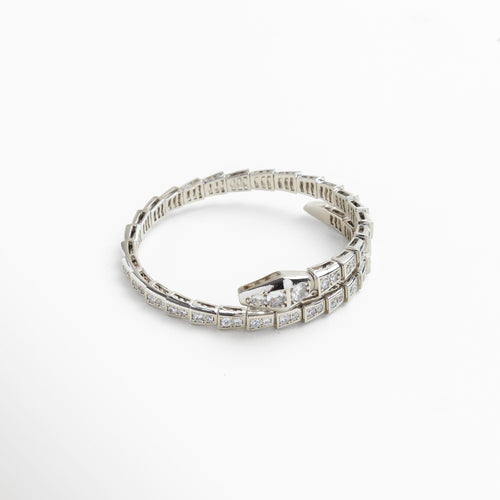 Primer plano de las incrustaciones de zirconias cúbicas que simulan escamas, Detalle del cierre con forma de cabeza de serpiente pulida, Textura articulada que aporta movimiento y flexibilidad, Acabado pulido en oro blanco con brillo metálico delicado, Detalle de los cristales brillantes en superficie reflectante